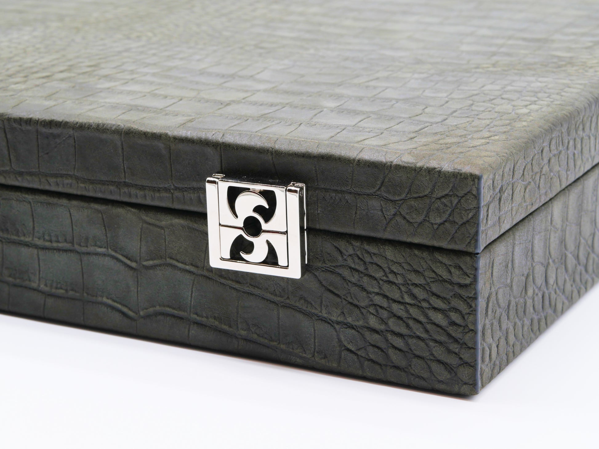 Close up of a black crocodile-embossed leather poker case corner with a silver latch.