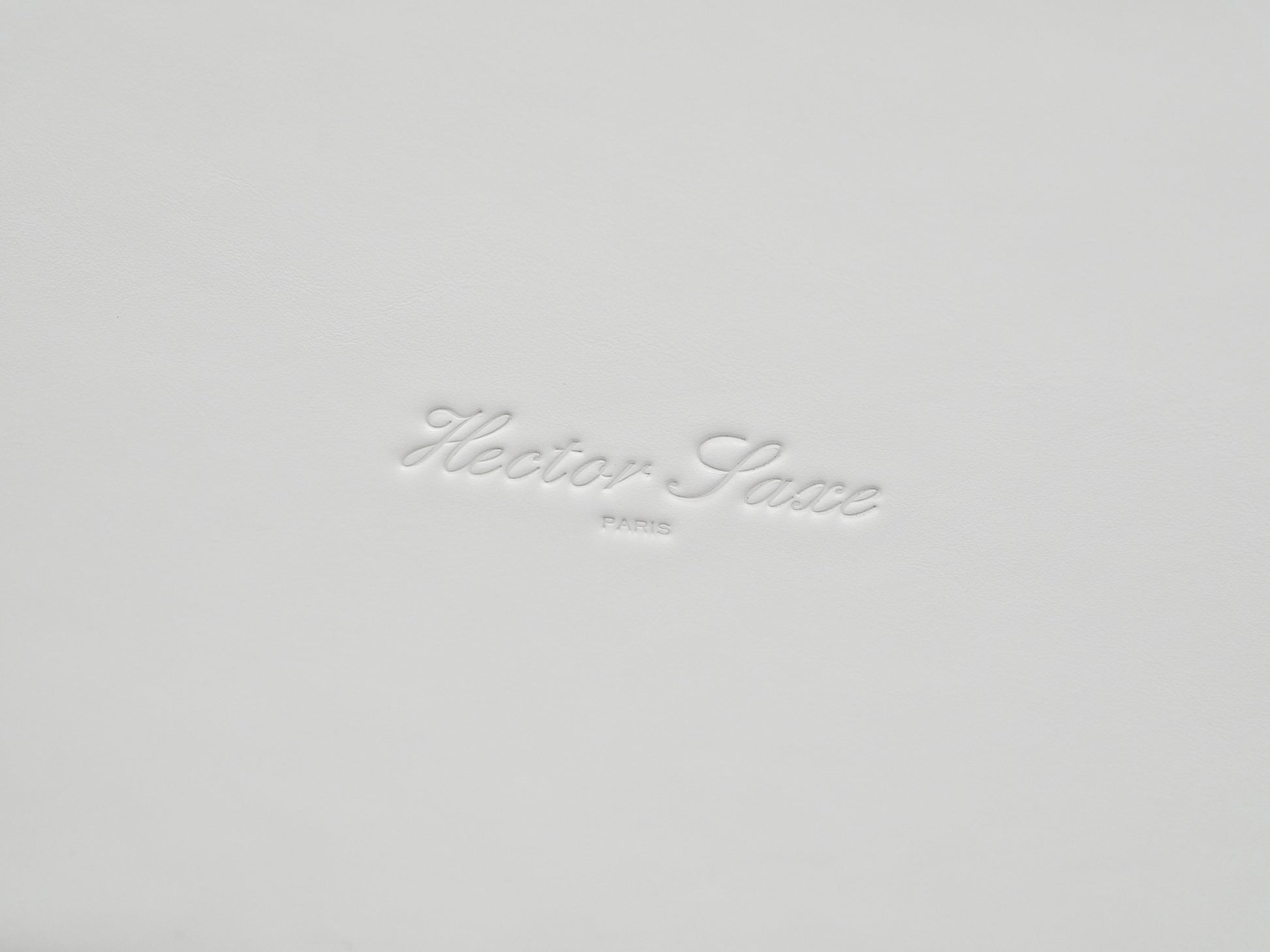 White leather gift box lid with embossed cursive brand name.
