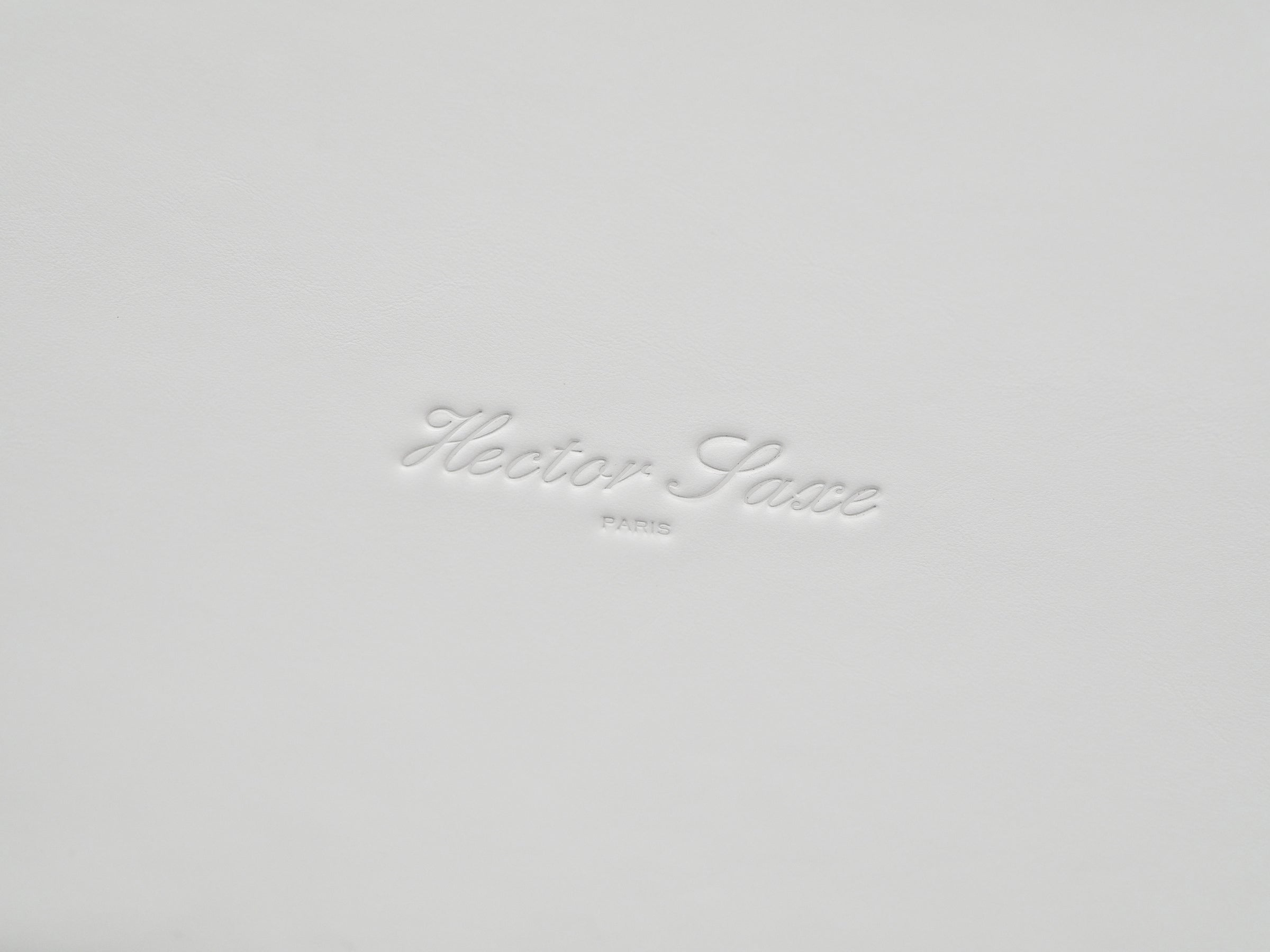 White leather gift box lid with embossed cursive brand name.