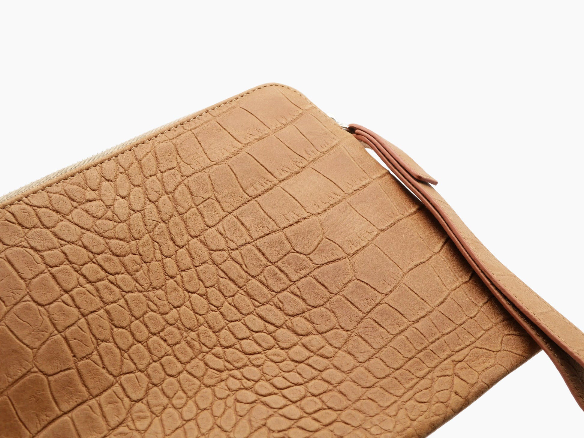 Close-up of amber crocodile-embossed leather on the lifestyle pouch showing the textured pattern.