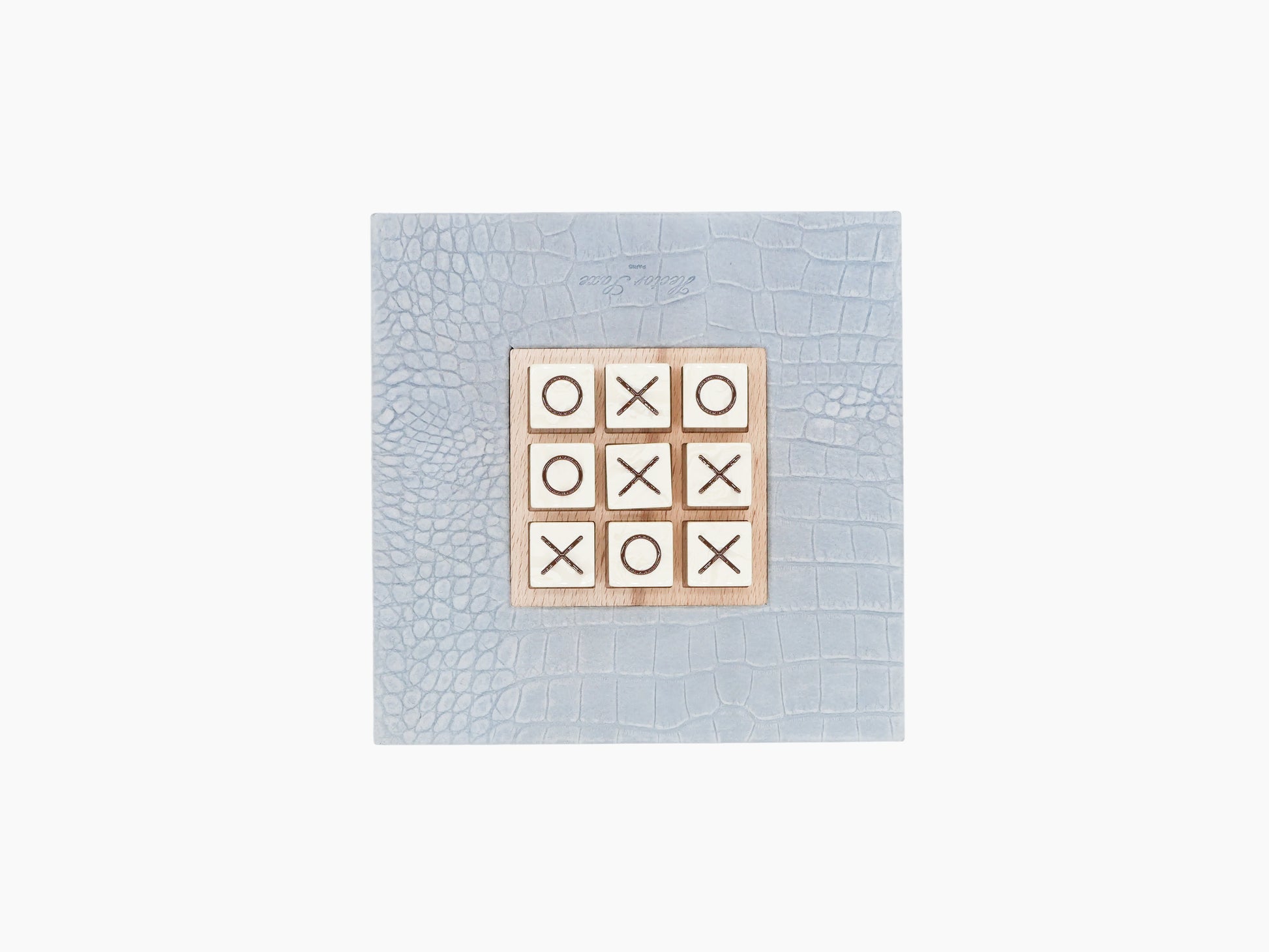 Tic Tac Toe Alligator Ciel set on a pale blue alligator-embossed leather base with marble X and O tiles.