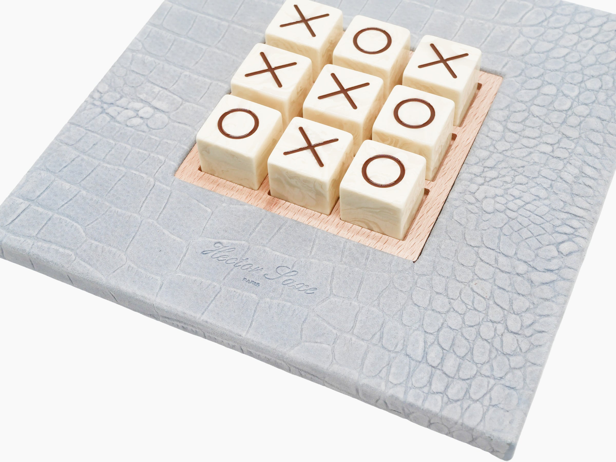 Nine ivory marble blocks arranged in a tic tac toe grid on an olive wood base, set in pale blue alligator-embossed leather.
