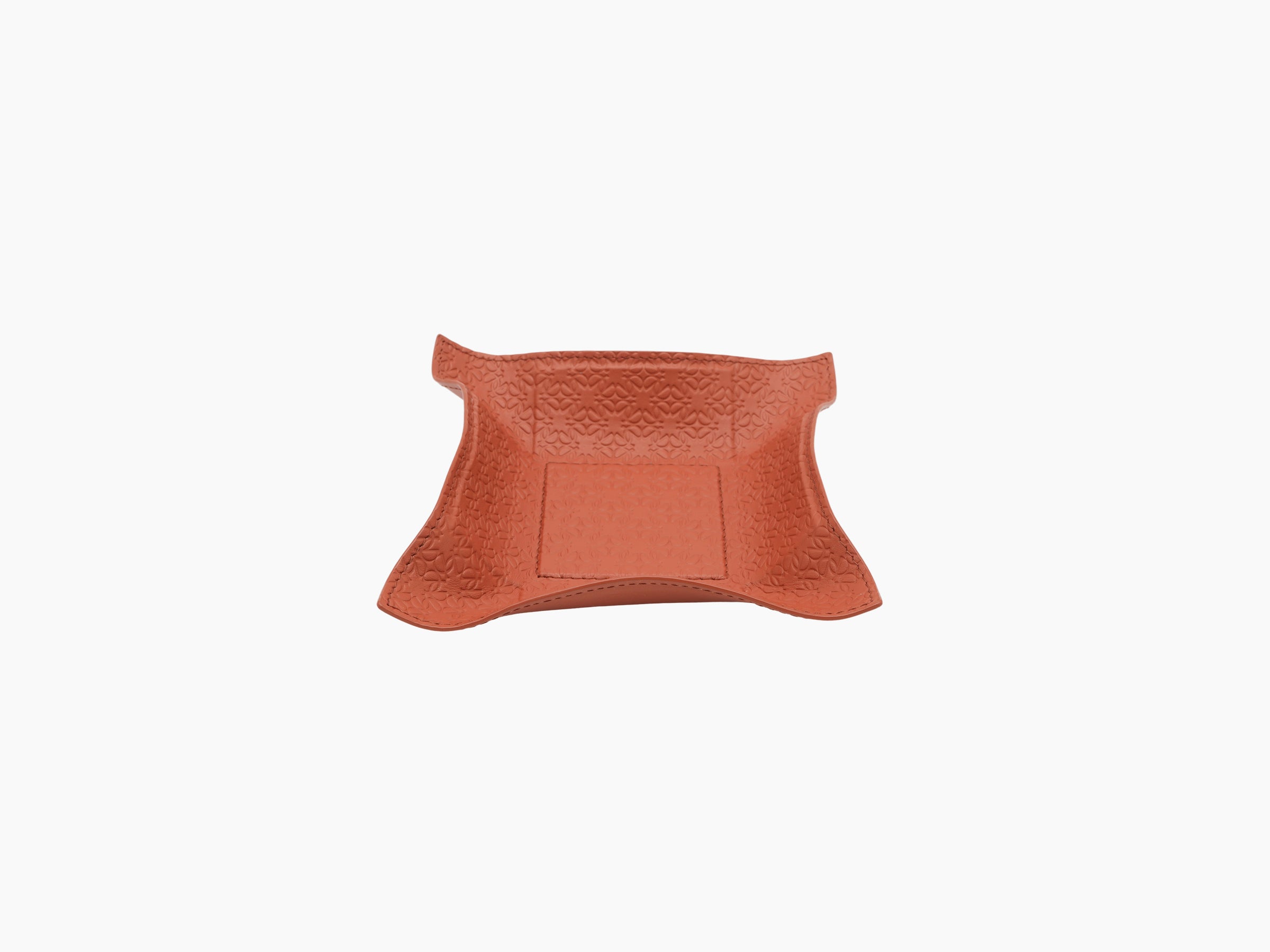Coral leather valet tray with embossed monogram pattern and curved flared edges