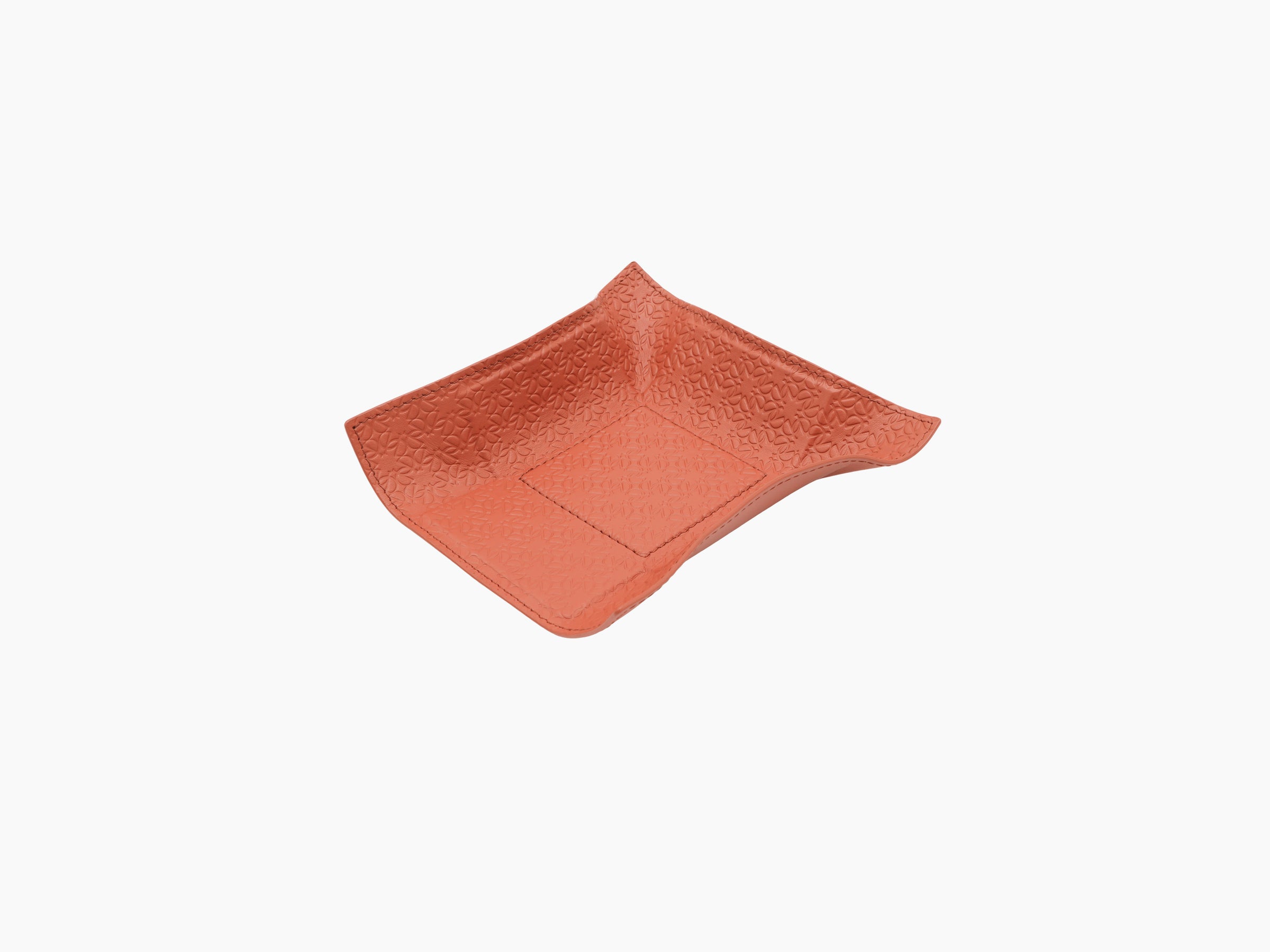 Close up of coral leather valet tray highlighting embossed pattern and curved corners
