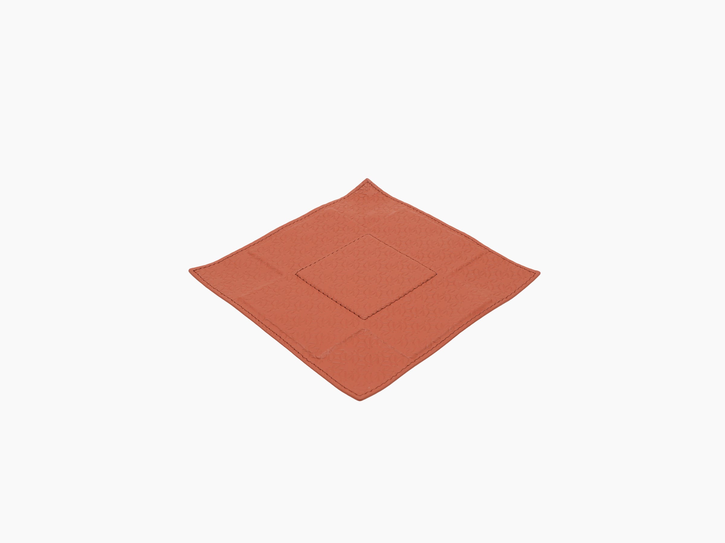 Diagonal view of coral leather valet tray with monogram embossing and a stitched diamond center patch