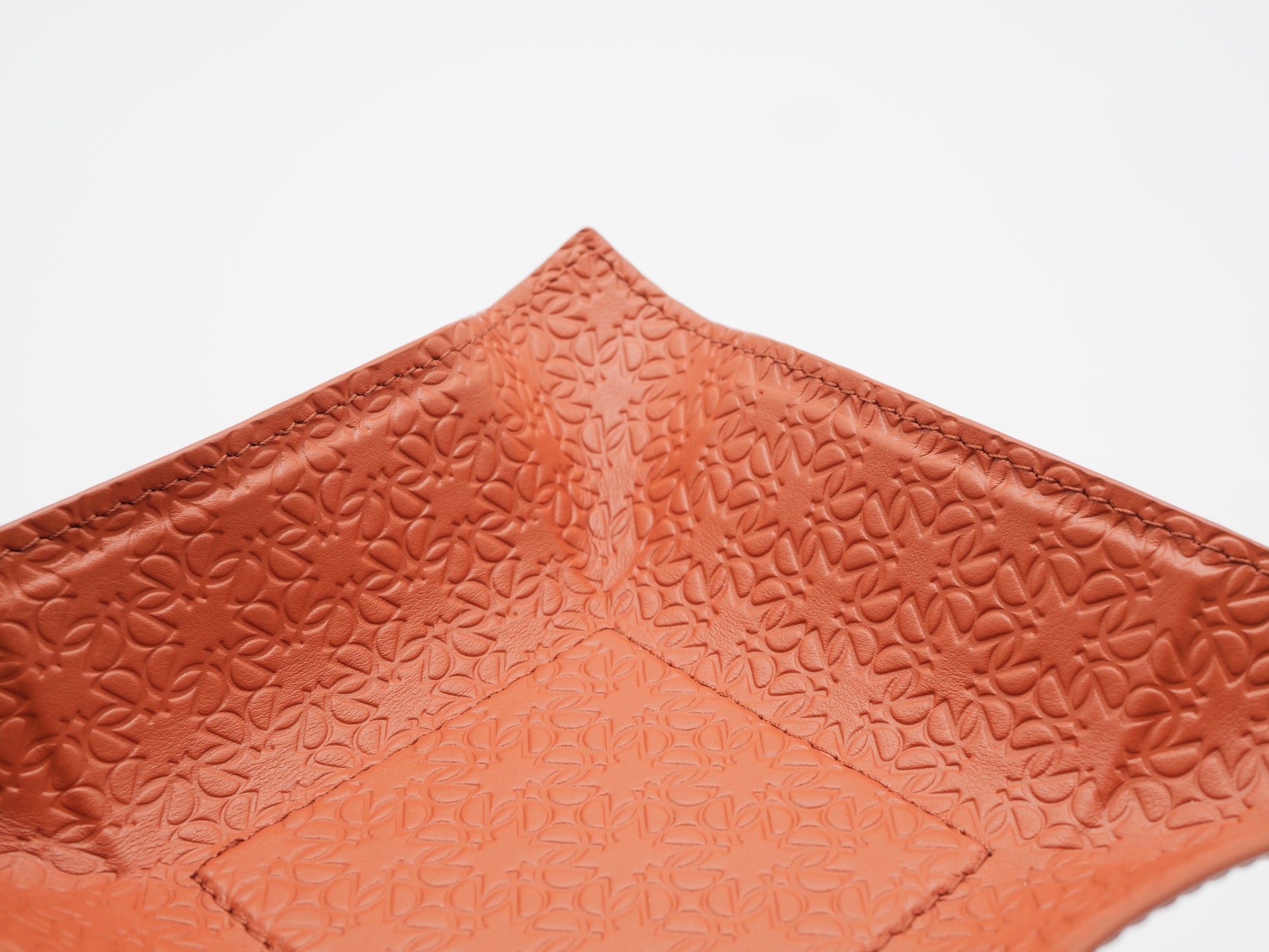 Close up of orange square valet tray corner with a monogram pattern