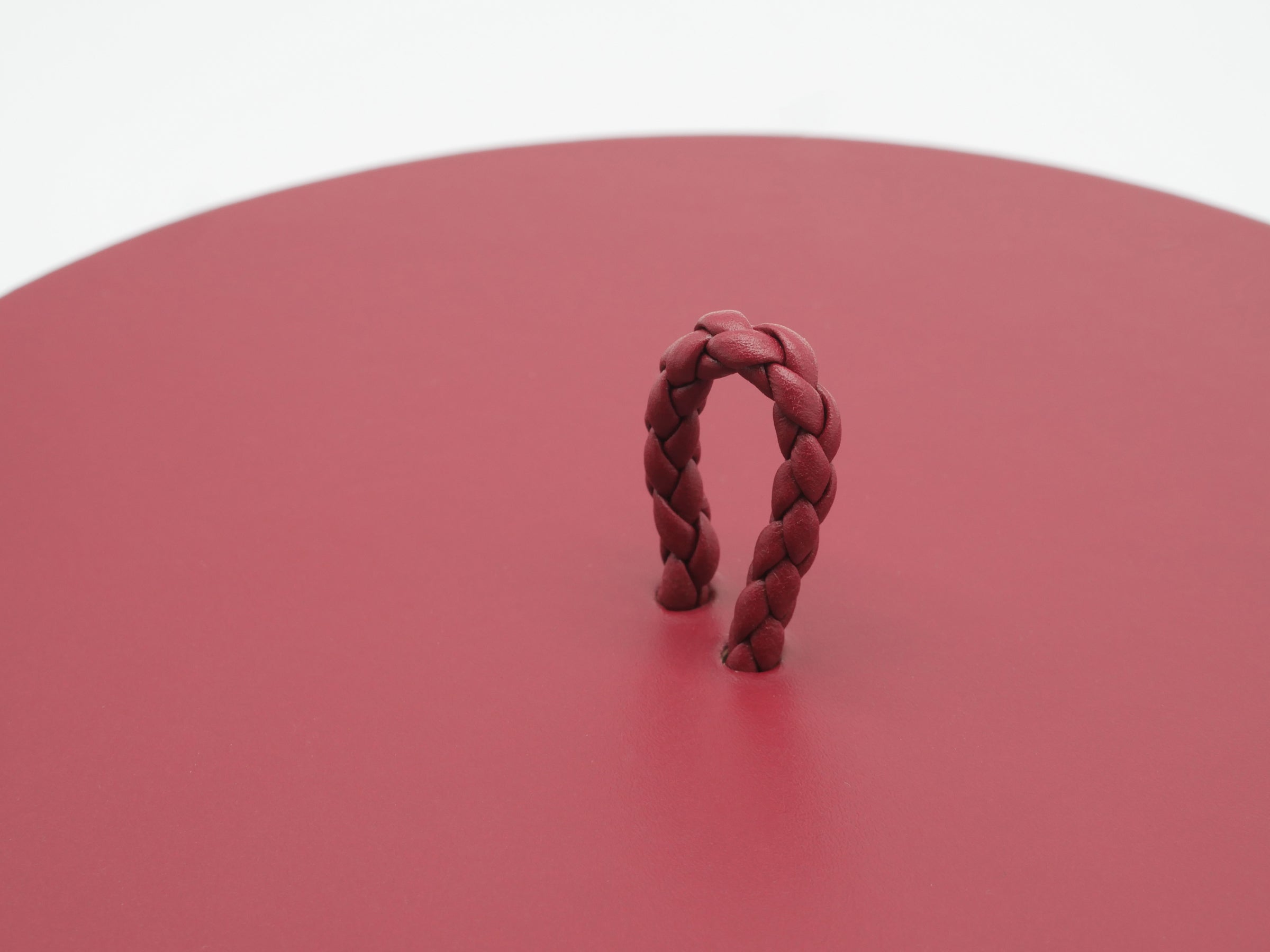 Close up of a burgundy Jana handwoven round box lid with a braided loop handle
