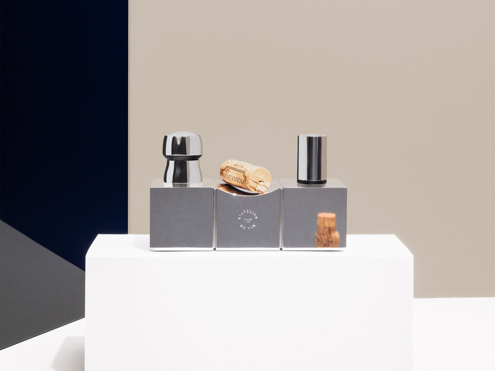 Bouchons Millésimés Silver display on three gray blocks with cork and chrome stoppers against a beige backdrop