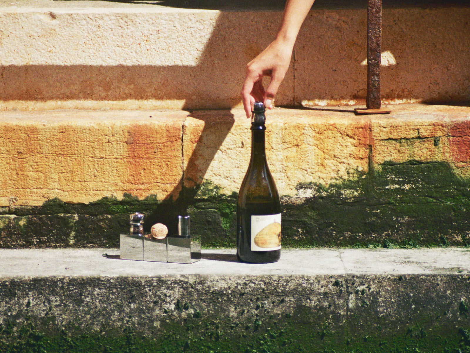 Outdoor scene with a wine bottle and a small cork display on a stone ledge.