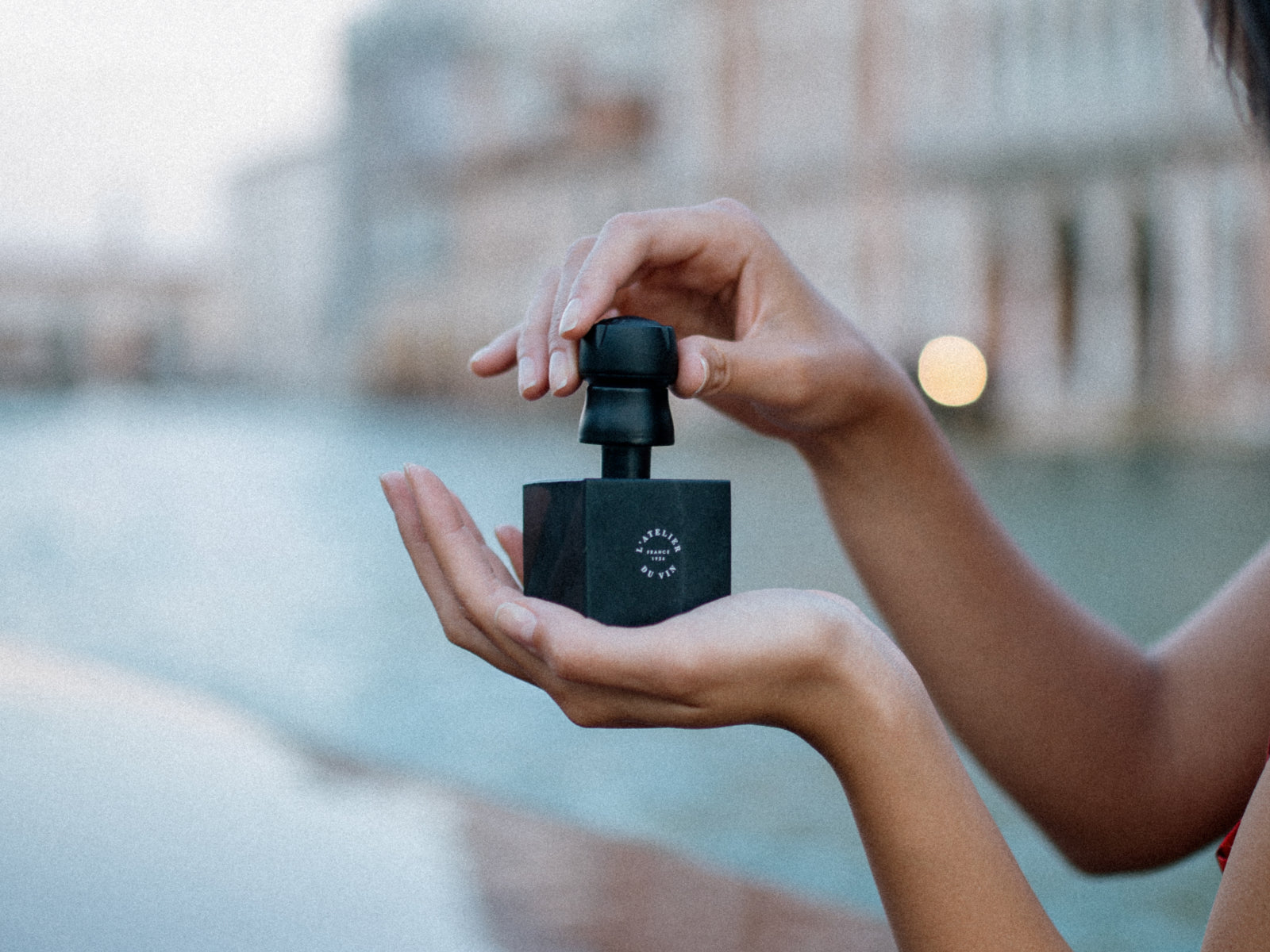 Hands hold a Bubble Cork stopper beside its black presentation box outdoors by the water