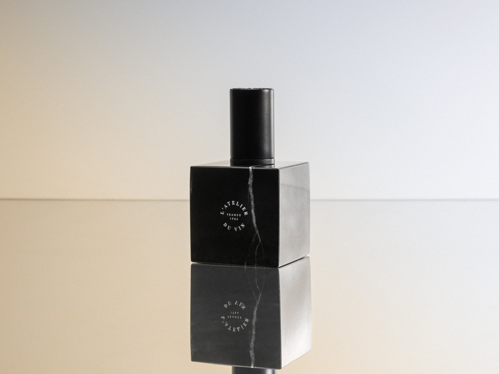 Le Bouchon Black wine stopper upright on a black square pedestal with a cylindrical top.