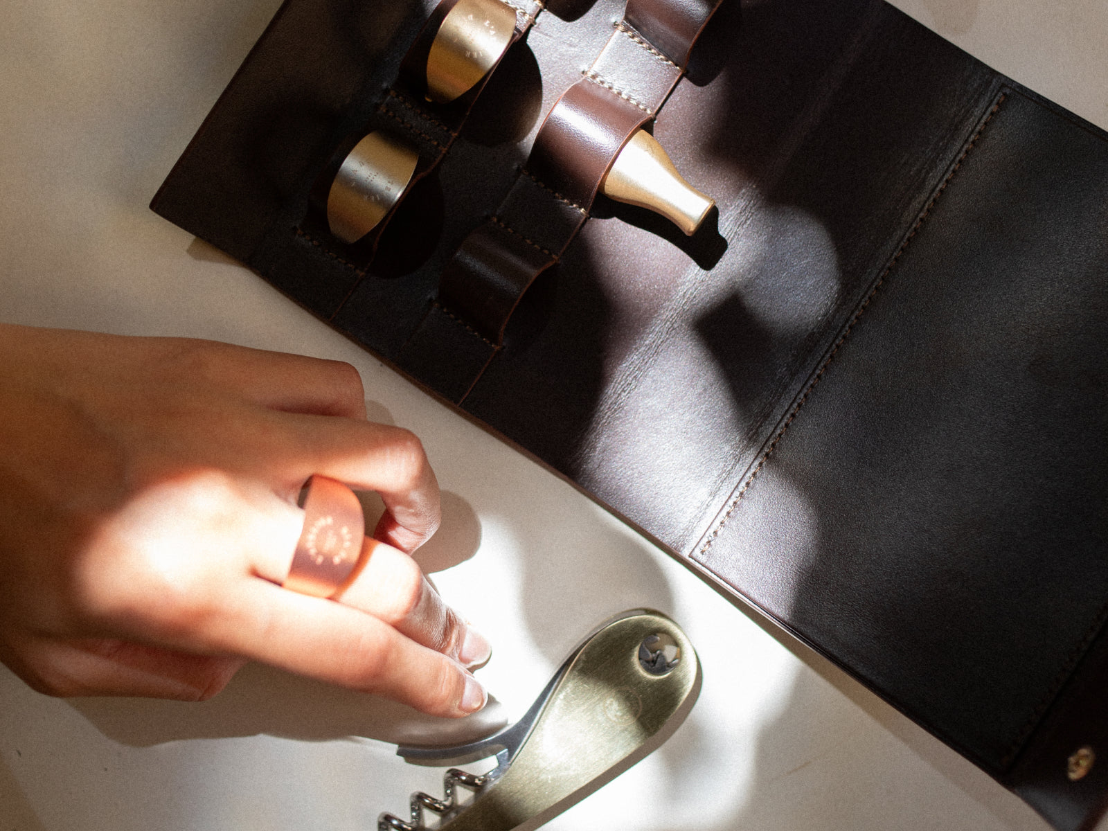 Dark leather wine accessories case open to reveal six tools including stoppers and rings