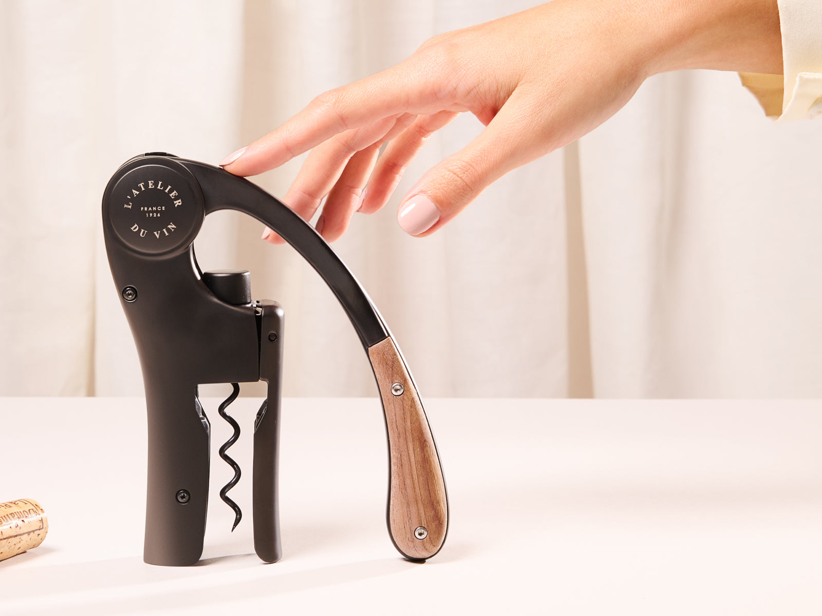 Oeno Motion Wood & Black wine opener with curved wooden handle and black body being prepared to uncork