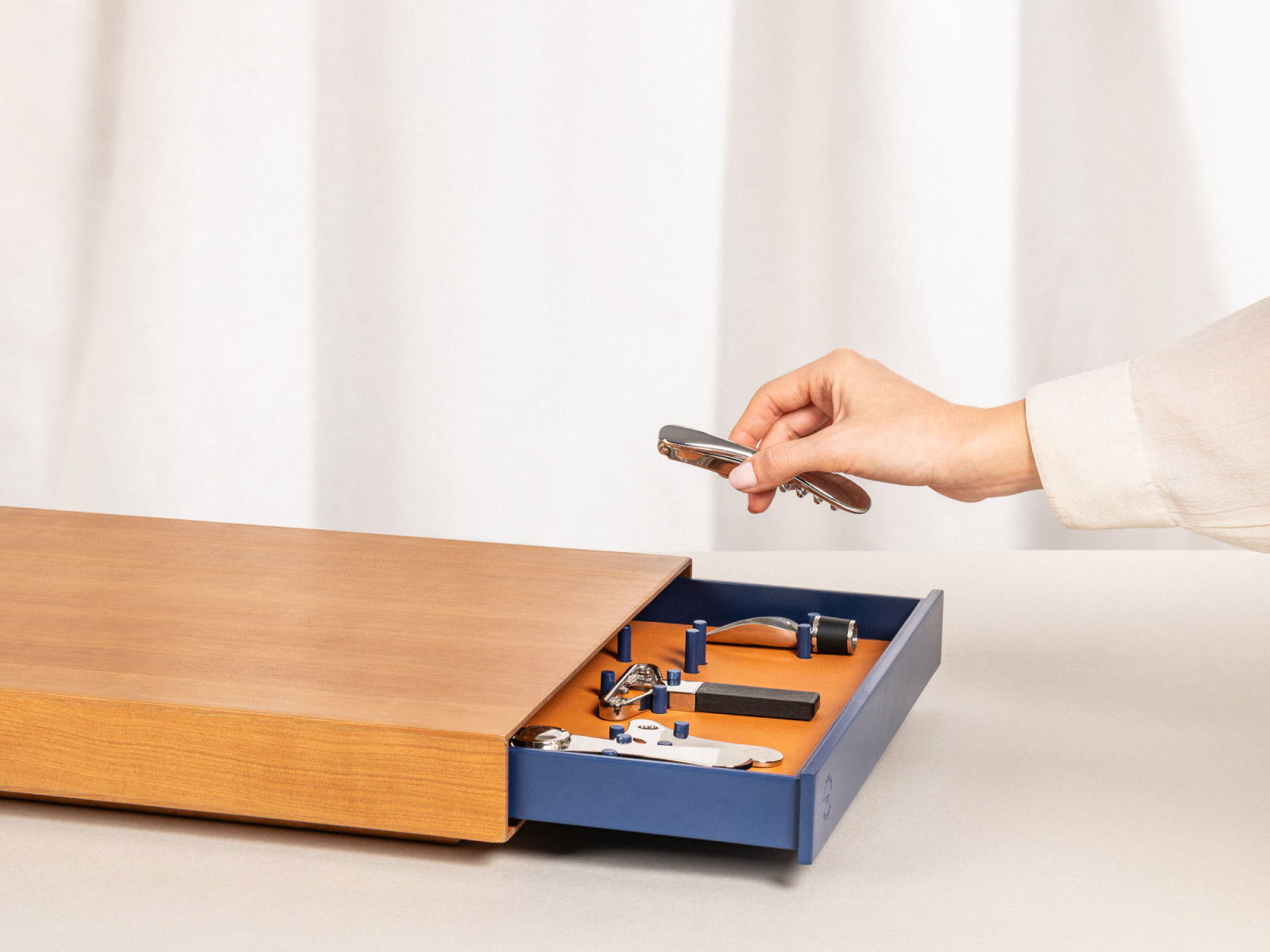 Le Plateau wine service set in a wooden box with blue interior; a hand holds a corkscrew tool over the tray.