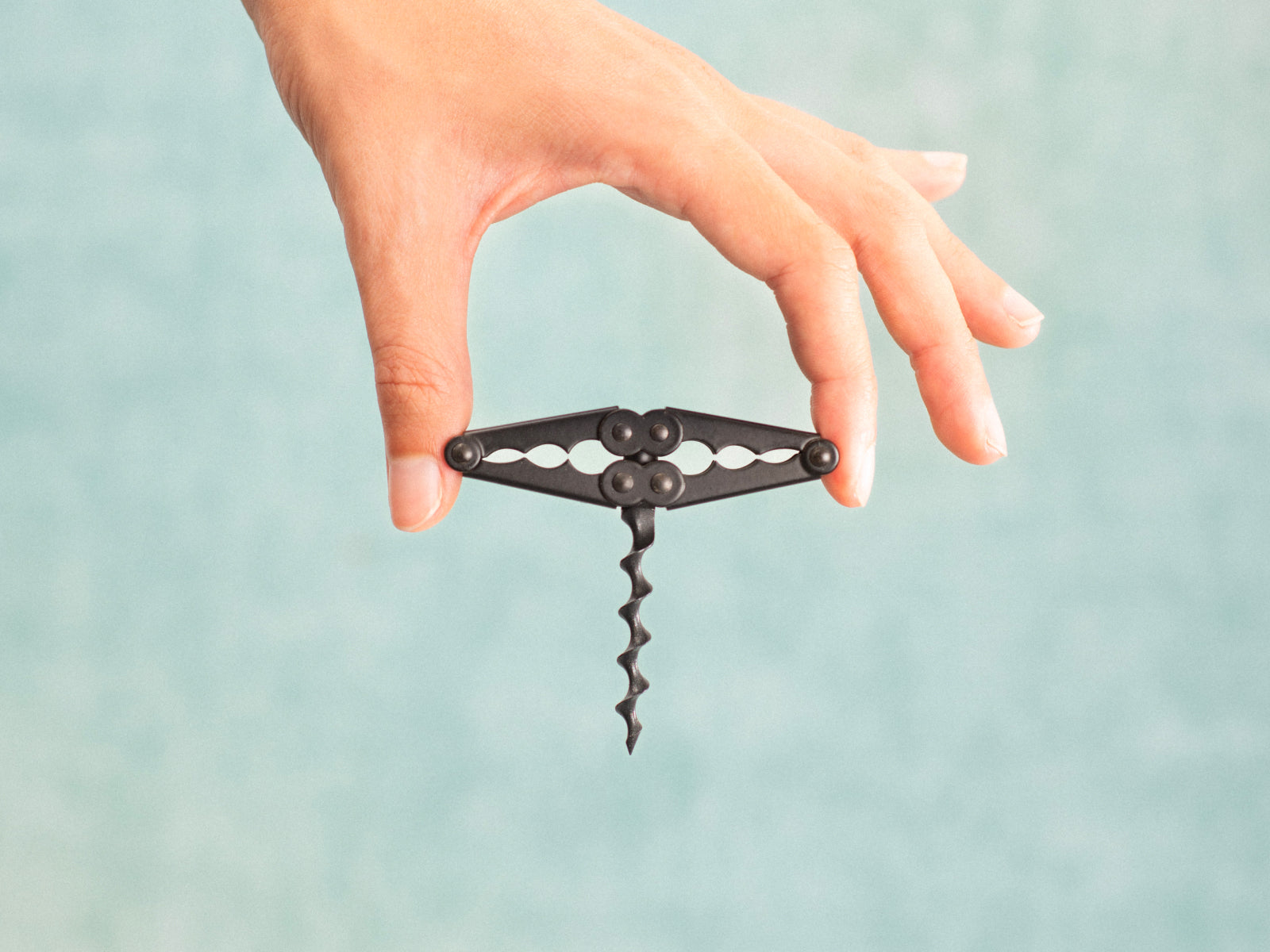 Close up of a hand gripping the black Pocket Collector corkscrew with the spiral worm extended.