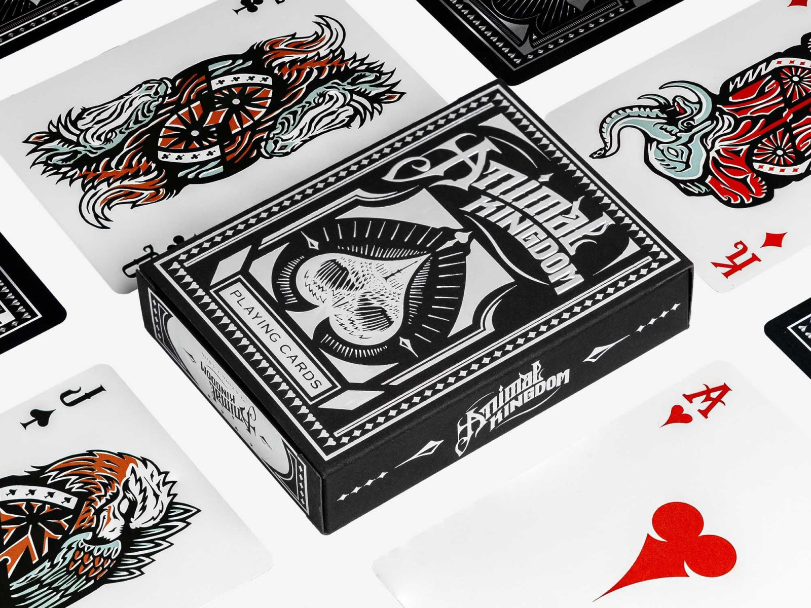 Black Animal Kingdom playing cards box with ornate white artwork surrounded by scattered cards
