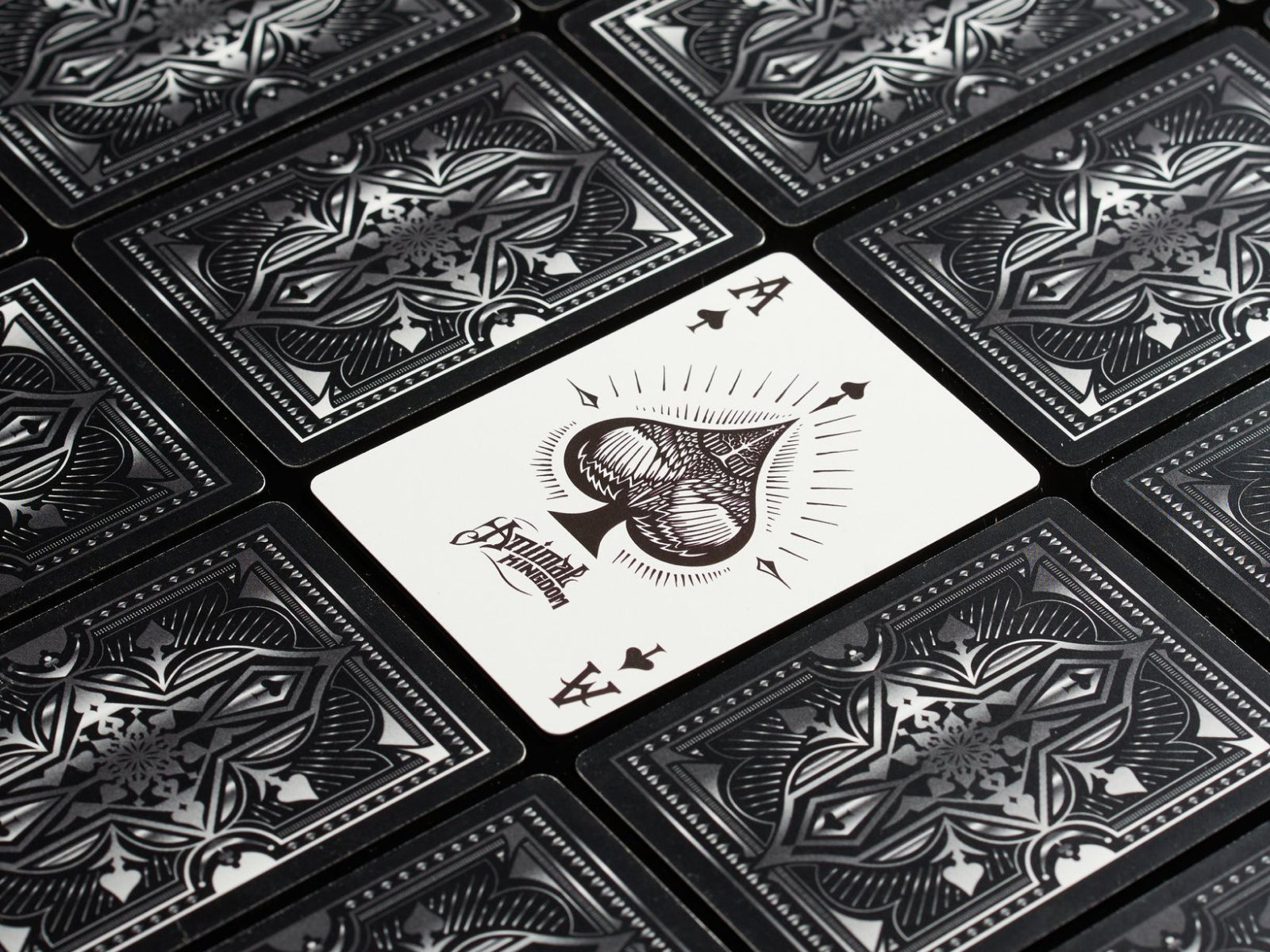 Close up of Animal Kingdom playing cards with intricate black and white backs and a white ace of spades card in the center.