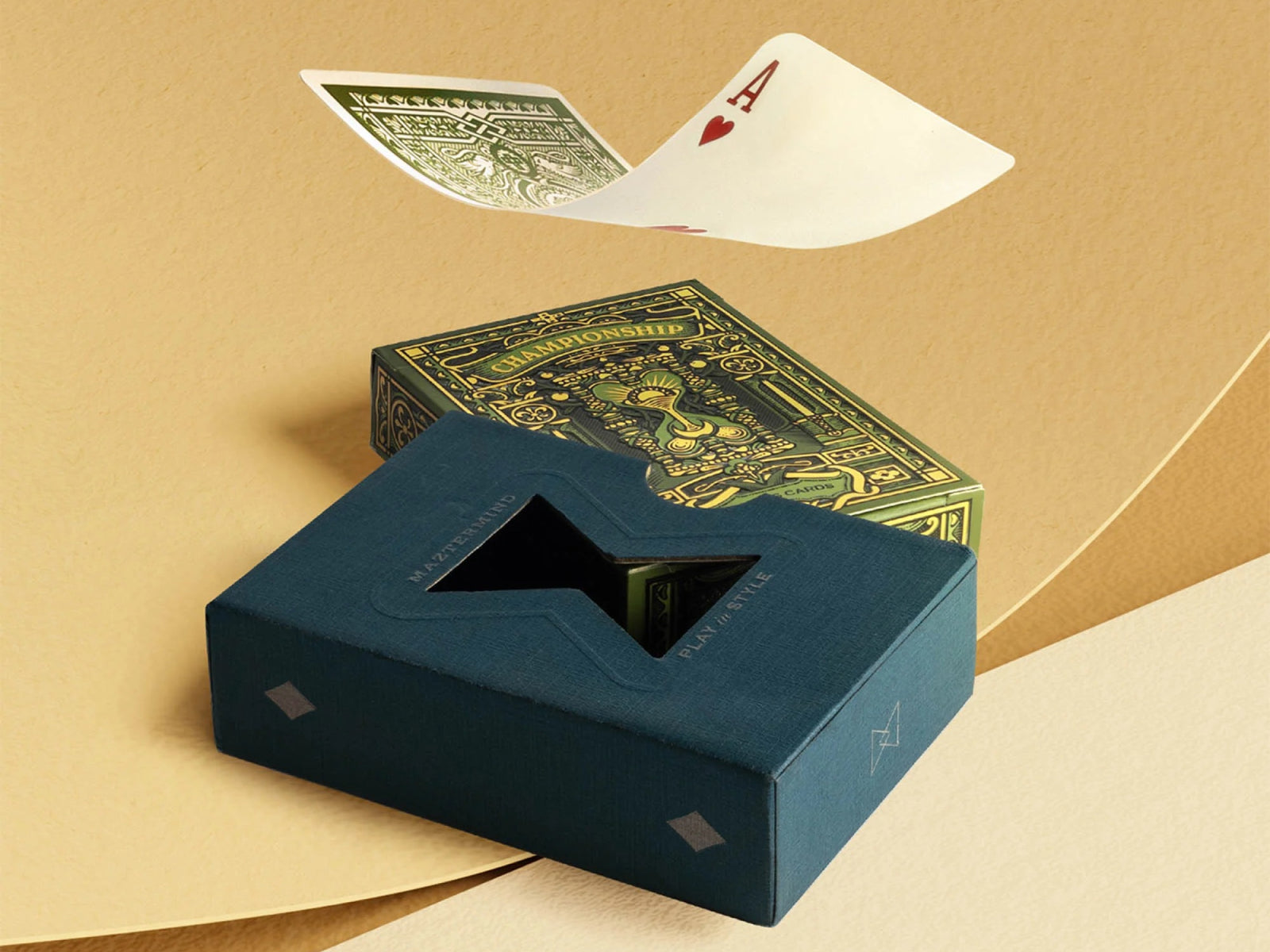 Blue tuck packaging with a star cutout beside an ornate green Championship playing cards box on a tan background.