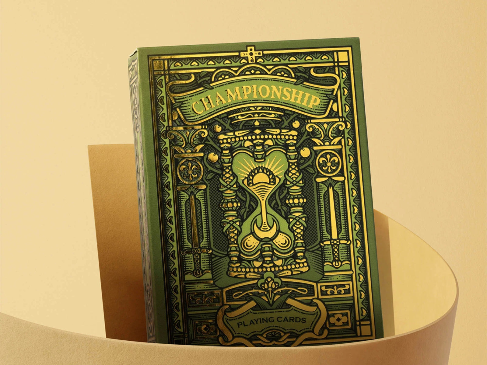 Green and gold ornate Championship playing cards box with intricate detailing against a warm beige backdrop.