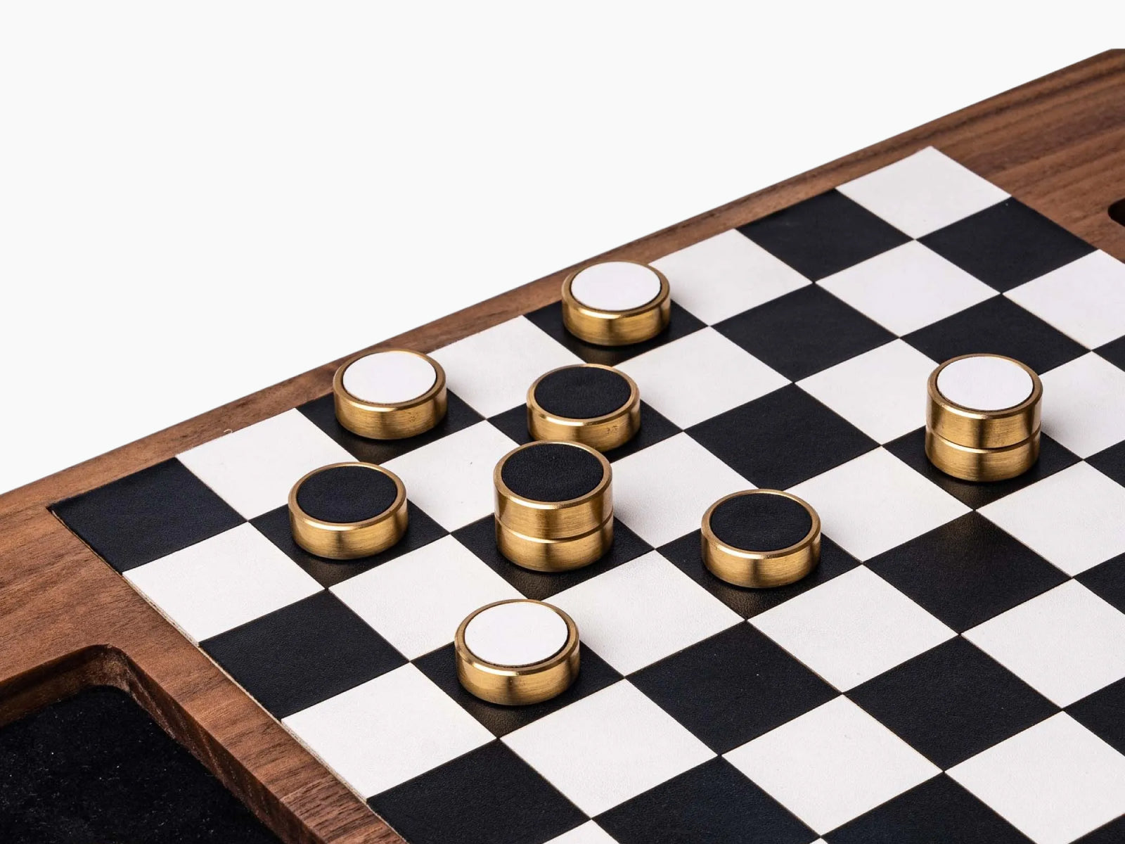 Close-up of brass-edged magnetic checkers on a black and white checkerboard set in walnut.
