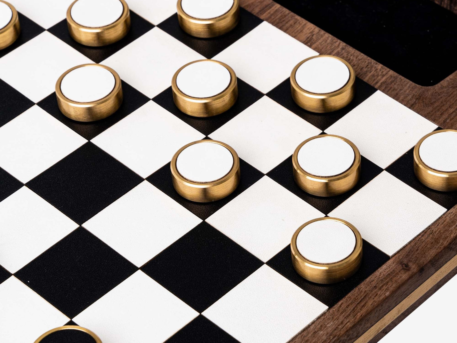 Detailed view of gold-rimmed magnetic pieces arranged across a walnut framed checkerboard.