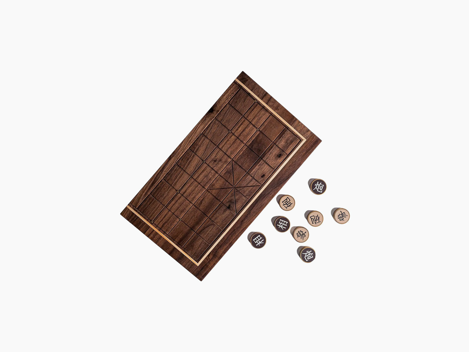Angled view of a walnut compact Chinese chess board with grid squares and several pieces scattered beside it.