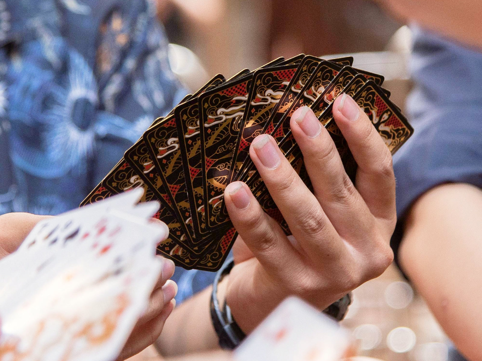 Hand holding a fanned Immortals playing cards deck with ornate gold and black backs