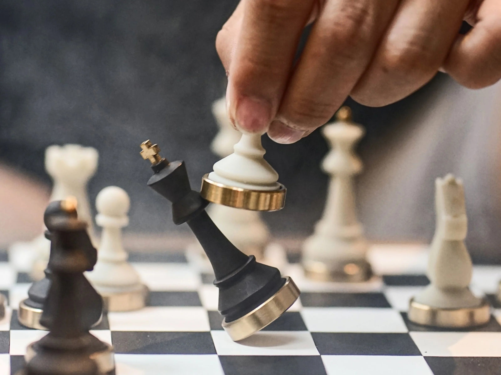Close up of a hand moving a white chess piece on a luxury chessboard with copper accents
