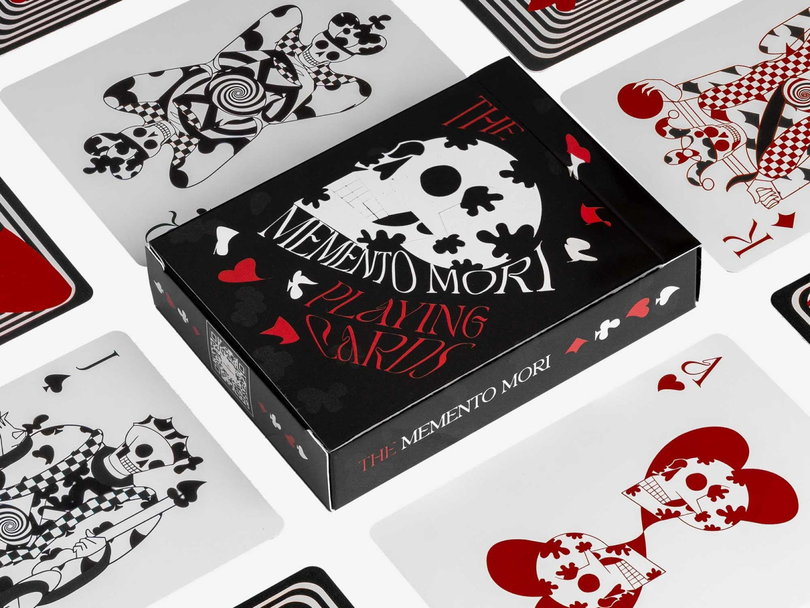 Memento Mori playing cards box surrounded by scattered red and black skull themed cards