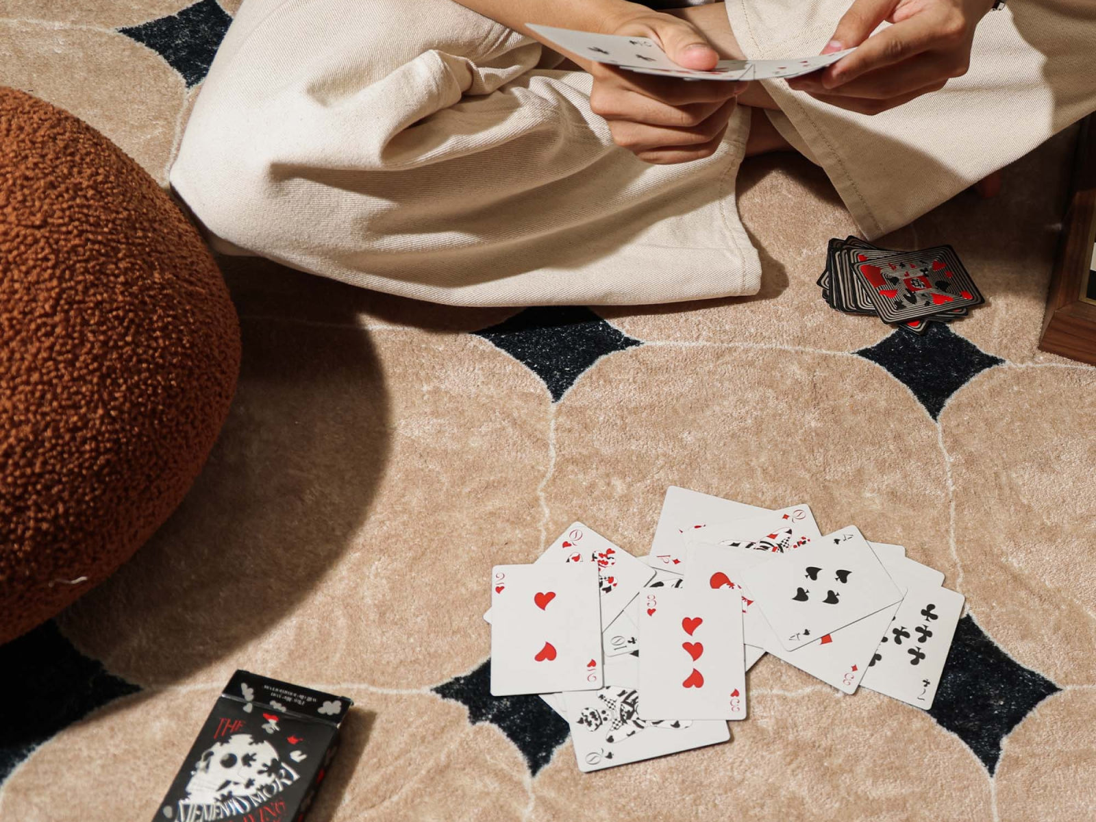 Player spreads Memento Mori playing cards on the floor as they prepare a hand.