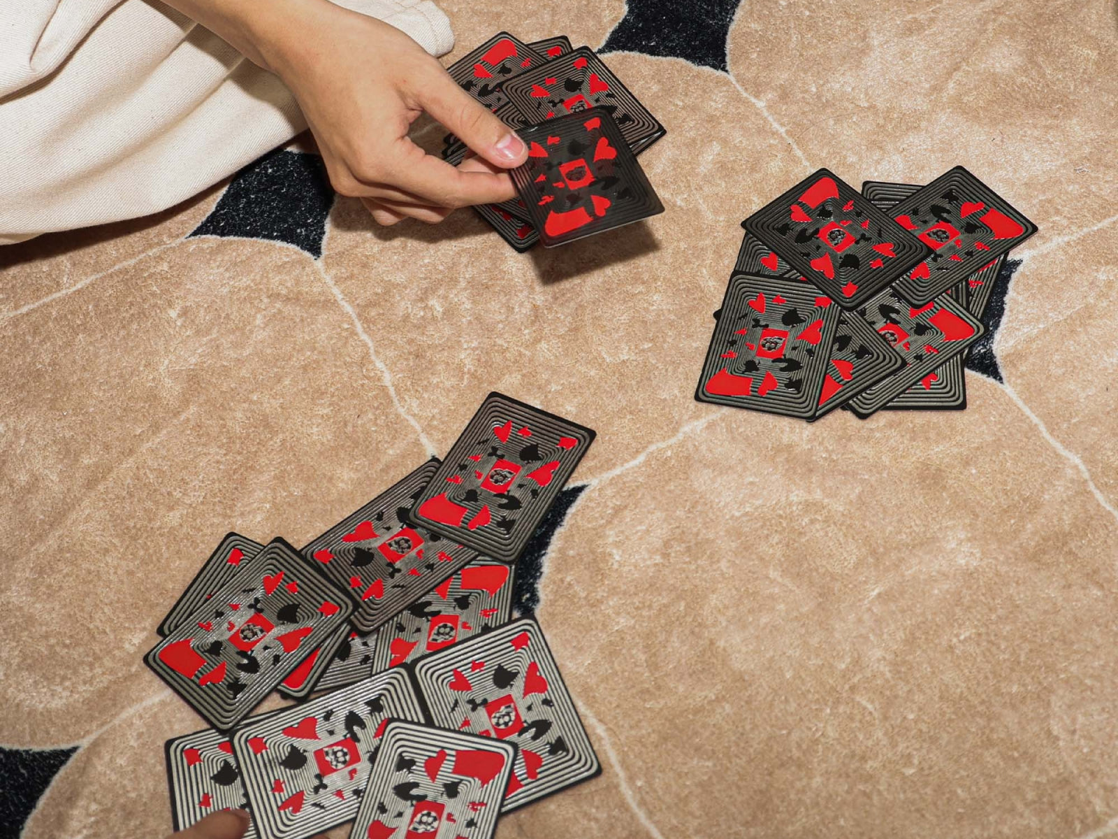 Hands deal Memento Mori playing cards on a beige carpet.