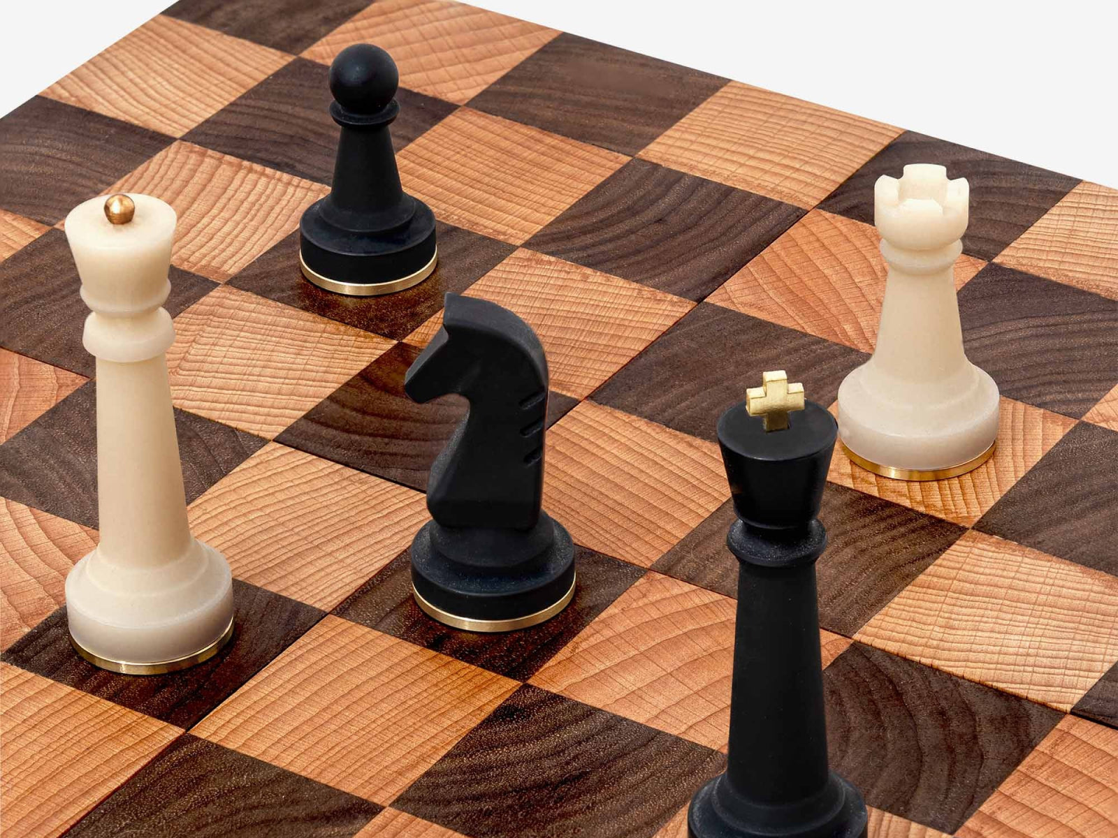 Close up of Nomad chess board with white king and rook and black knight on a walnut beech checkered board