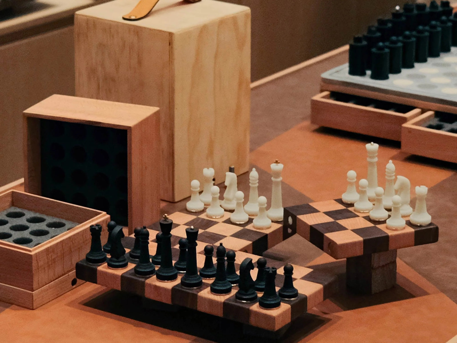 Tabletop view of Nomad portable chess set with boards and pieces arranged on a warm wood table and storage box in the background