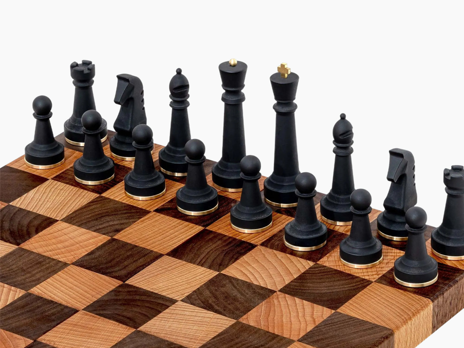 Close-up of Nomad portable chess set with black pieces on a two-tone wooden board and brass ring bases
