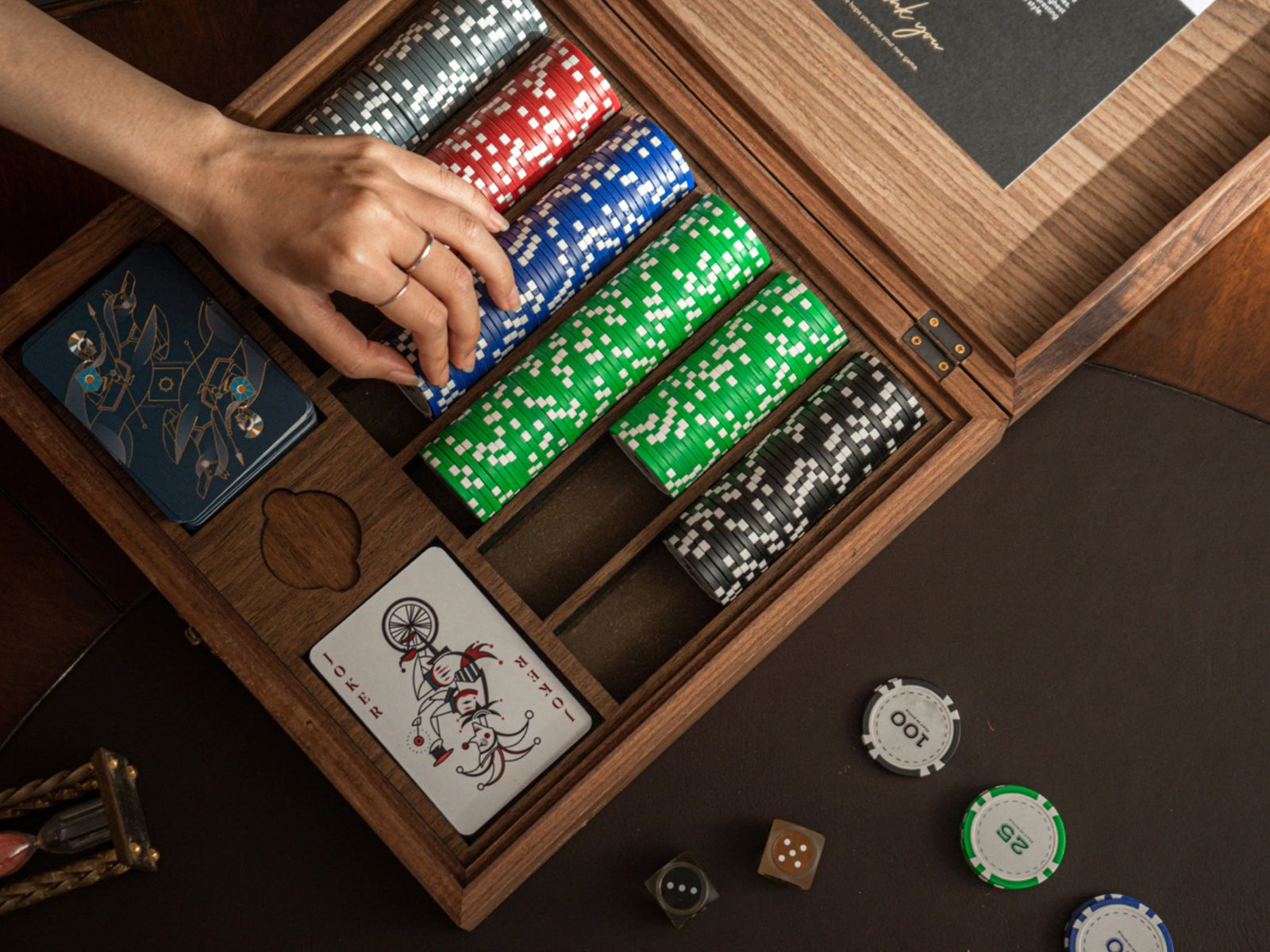 Poker chip set inside a walnut box with stacked red blue green and black chips and playing cards