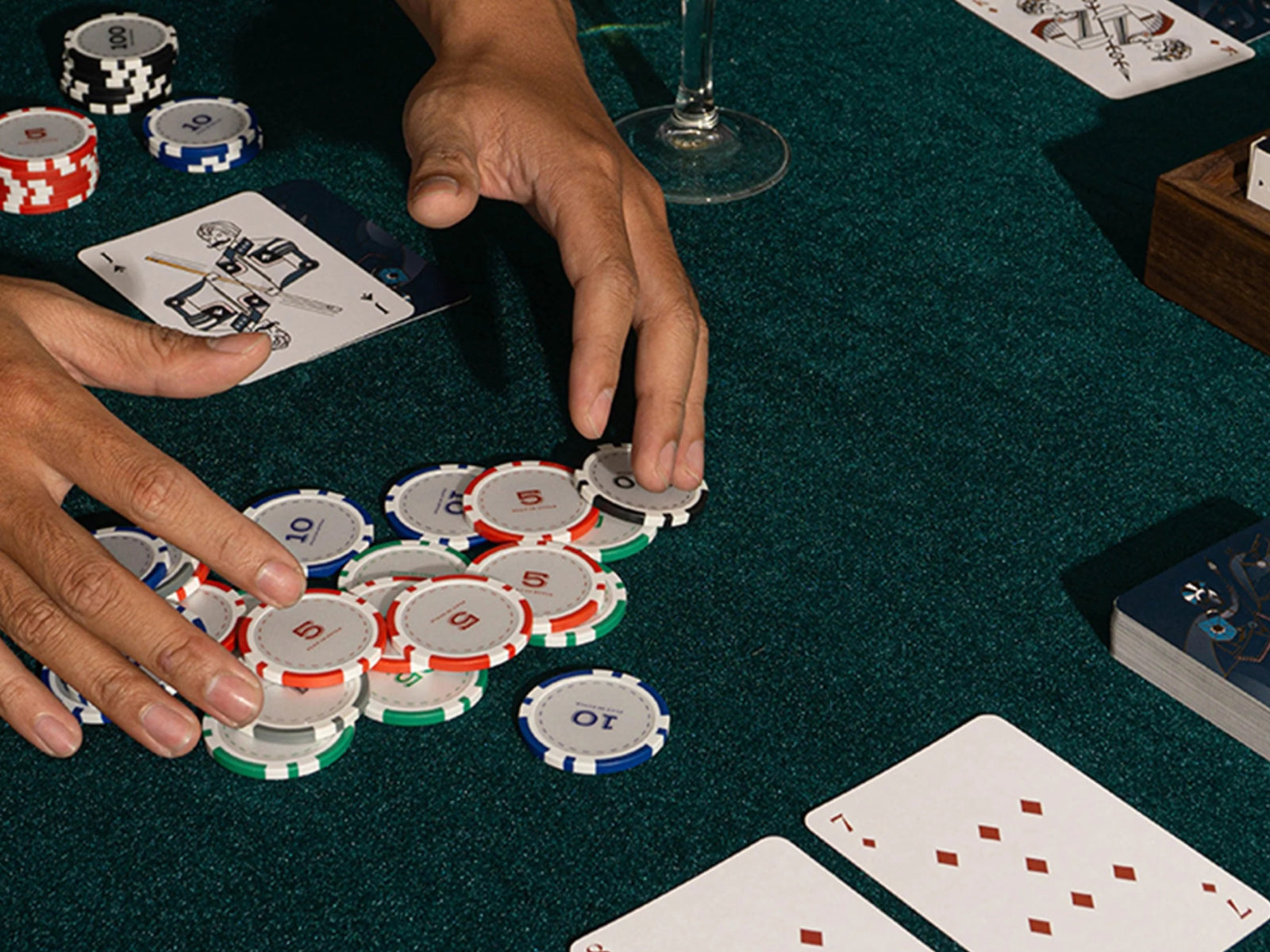 Close up of Bowtie Poker Chip Set on green felt with scattered poker chips and playing cards.