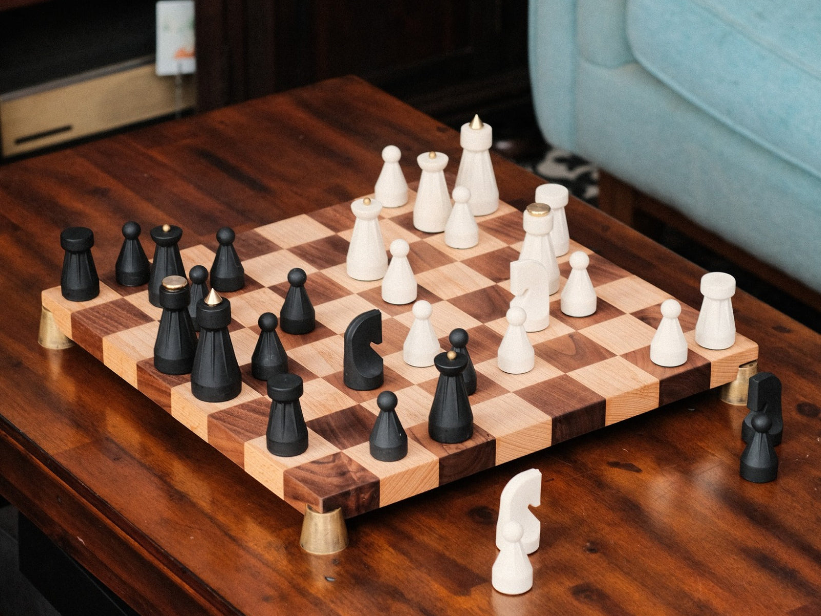 The Regal Chess Set on a two tone wooden chessboard with black and white sculpted pieces arranged for play.