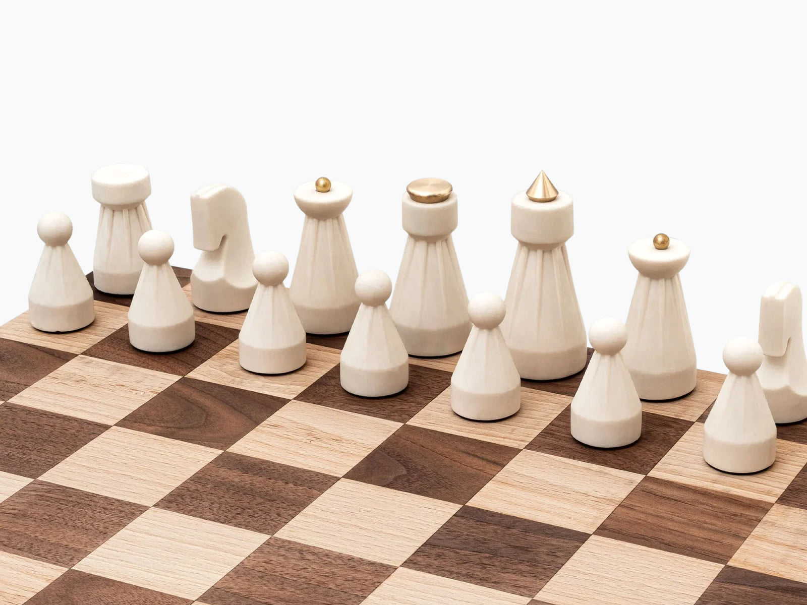 White carved chess pieces lined up on a two-tone wooden chessboard against a white background from The Regal Chess Set.