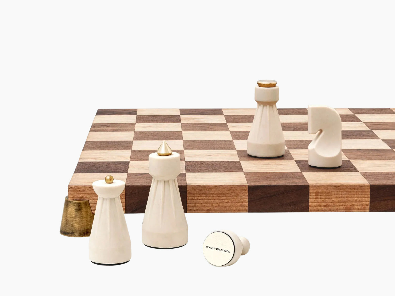 White carved chess pieces with brass accents on a two-tone wooden chessboard, with pieces arranged nearby from The Regal Chess Set.