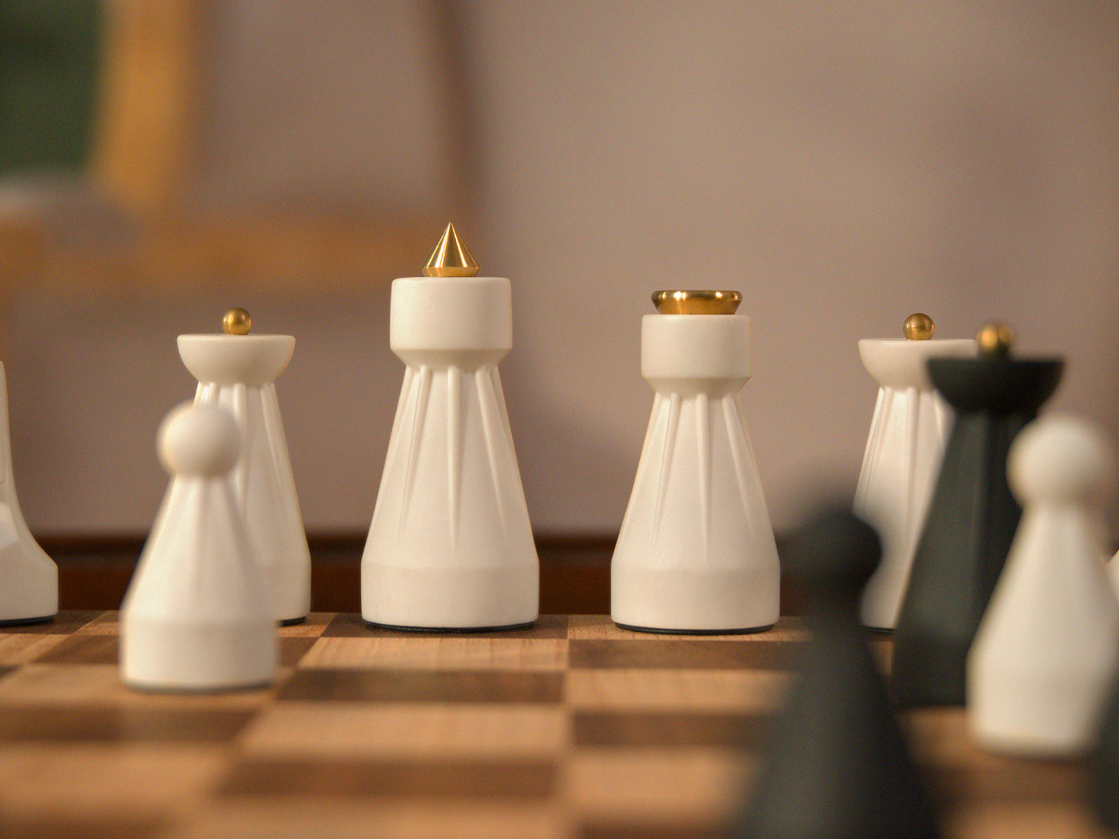 Close-up of The Regal Chess Set white pieces with gold accents on a wooden chessboard.