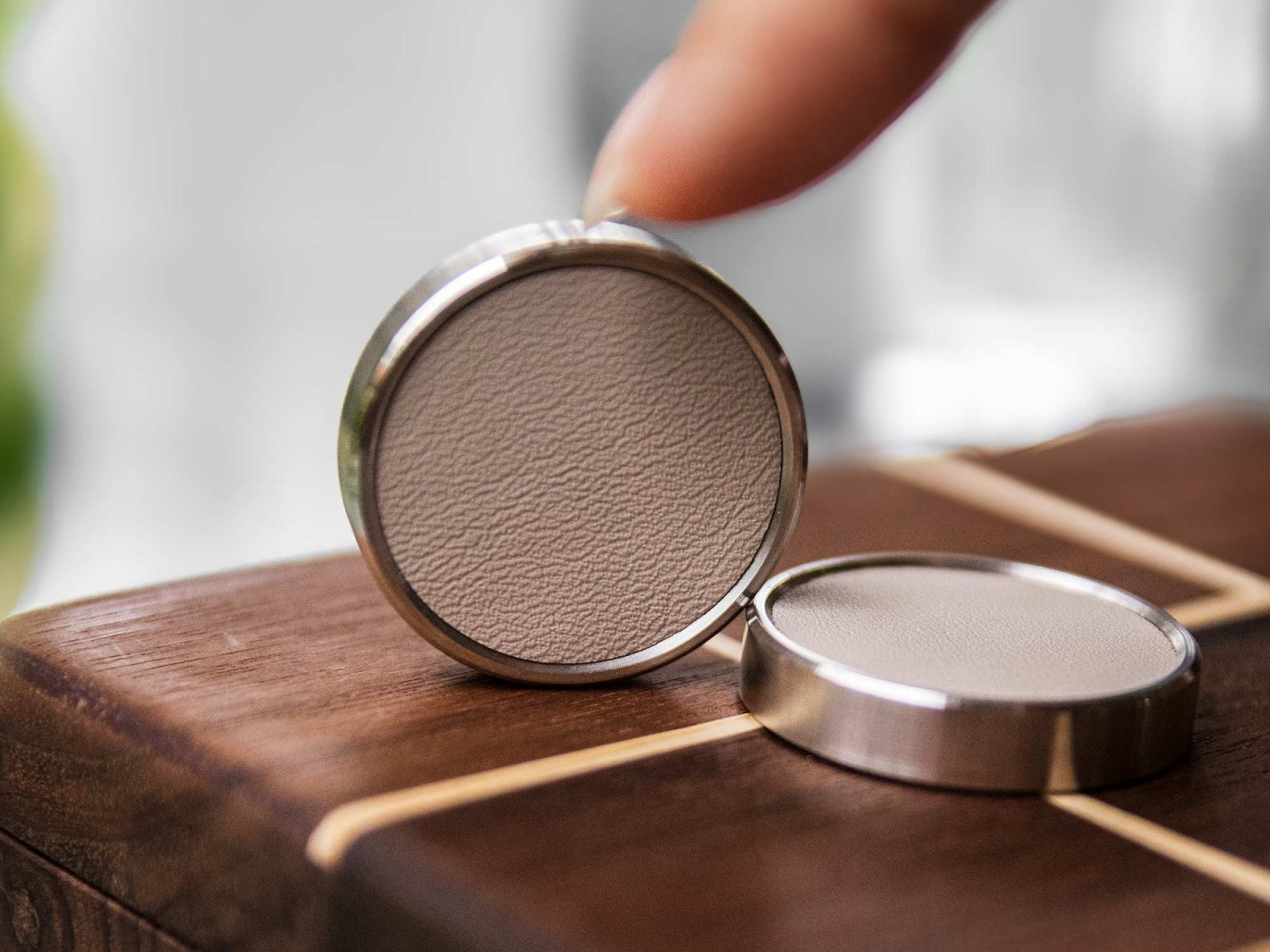 Open round metal case with beige leather interior resting on a wooden table