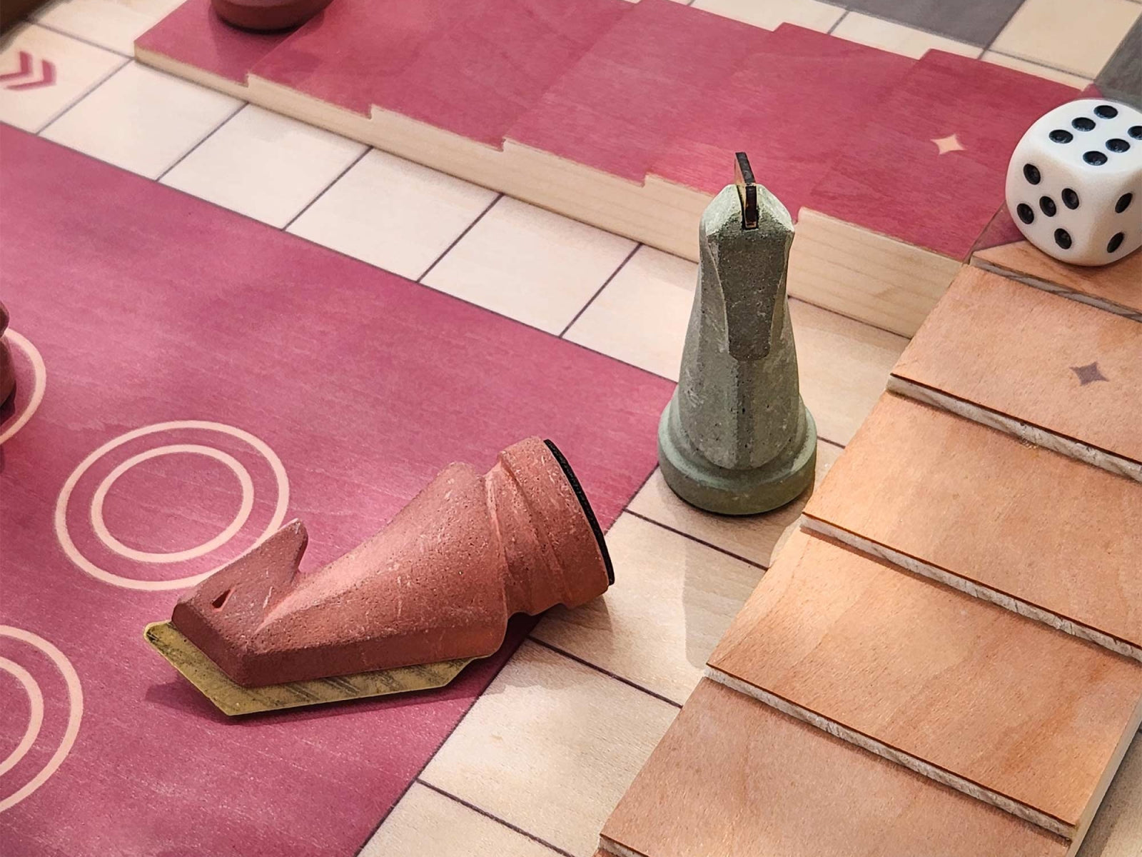 Close-up of red and pink board sections showing toppled red knight, upright green knight, and a white die on the Trojan Horse Race Ludo board.