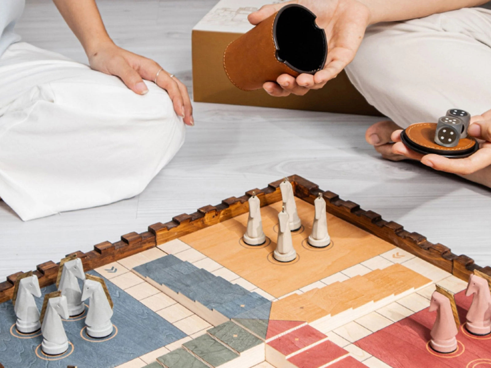People playing Trojan Horse Race Ludo on a pinewood board with cement pawns and a circular leather dice tray