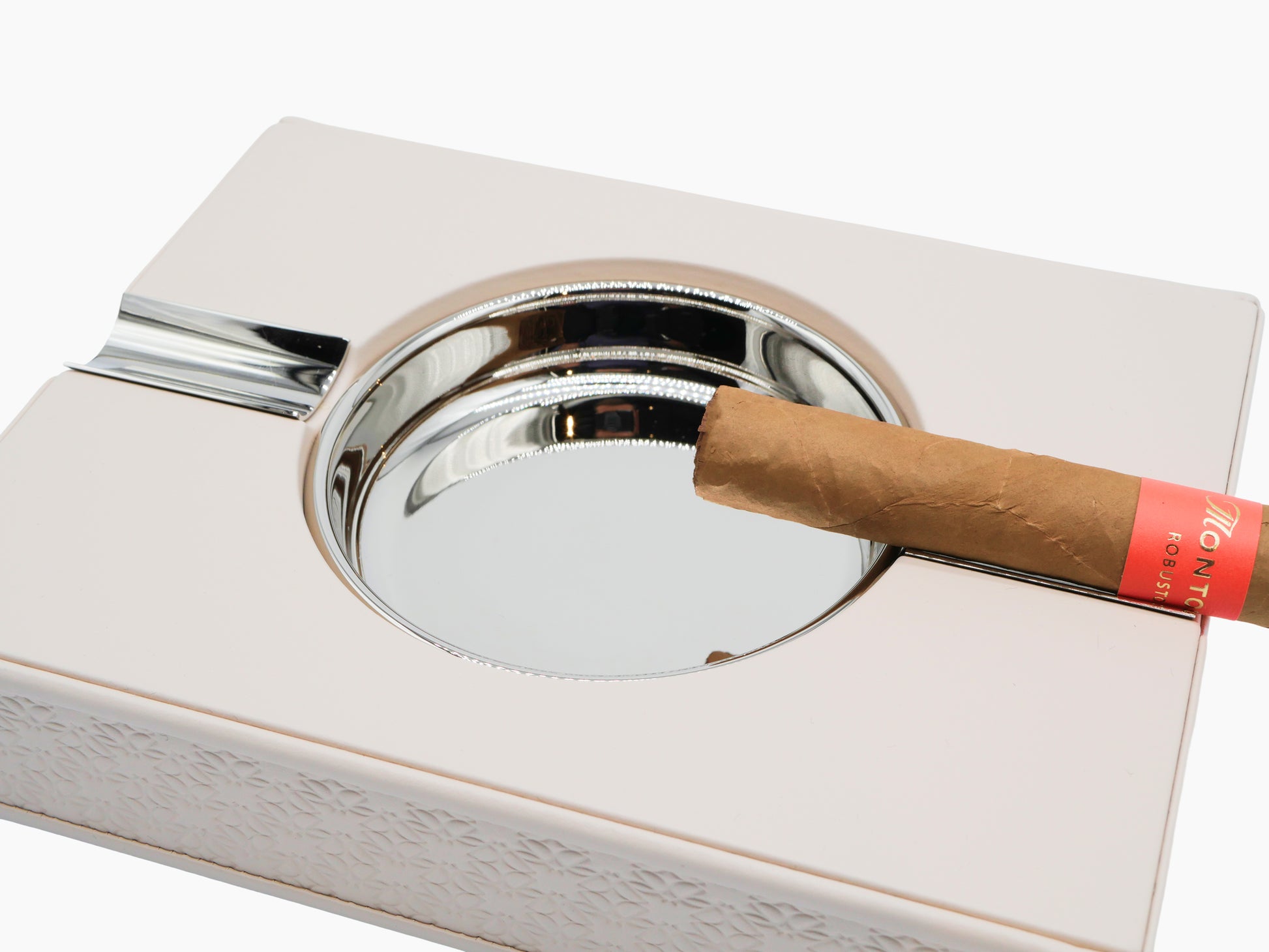 Monogram Table Ashtray in cream padded leather with palladium accents and a silver ash bowl holding a cigar.