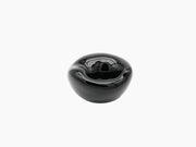 Small obsidian black hand blown glass vessel with a glossy rounded shape and inner concave opening.