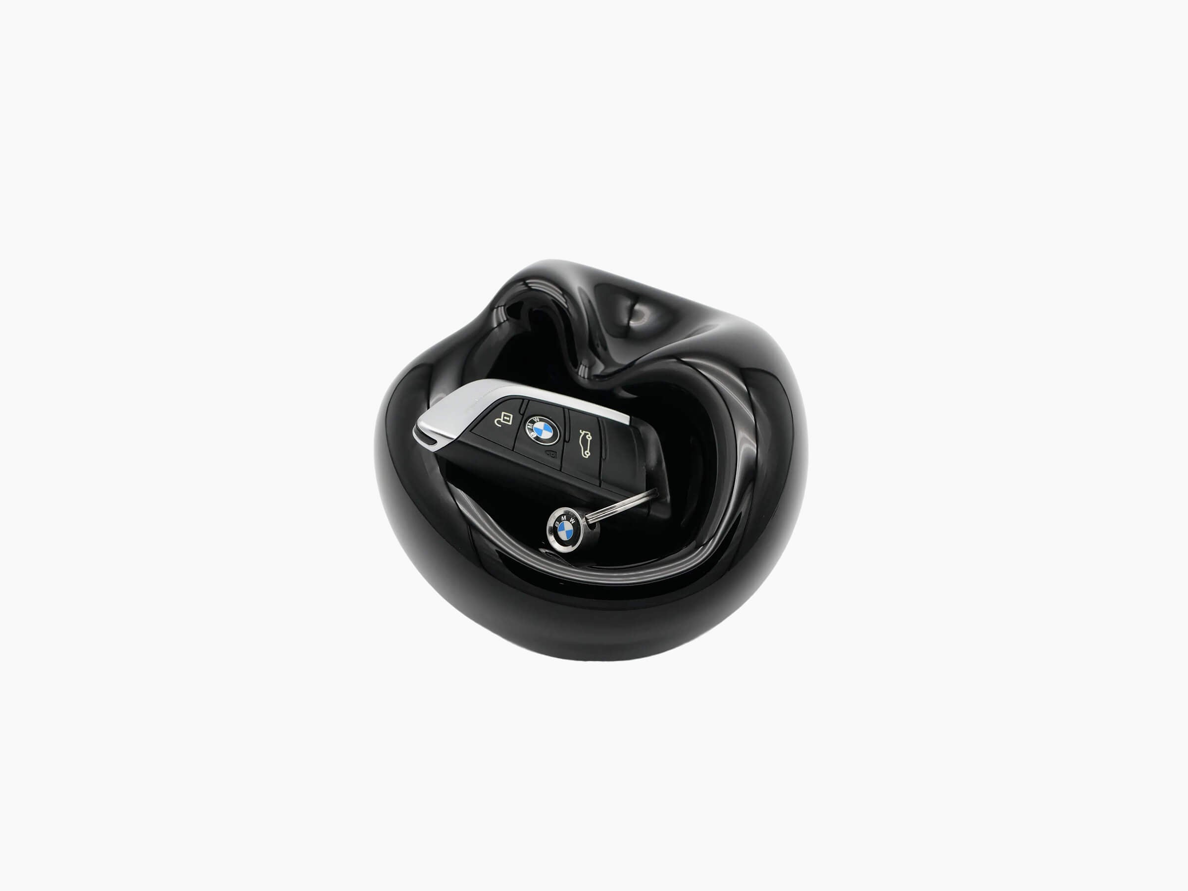 Large Obsidian Black Vessel hand blown glass with a curved bulbous form and a BMW key fob resting inside