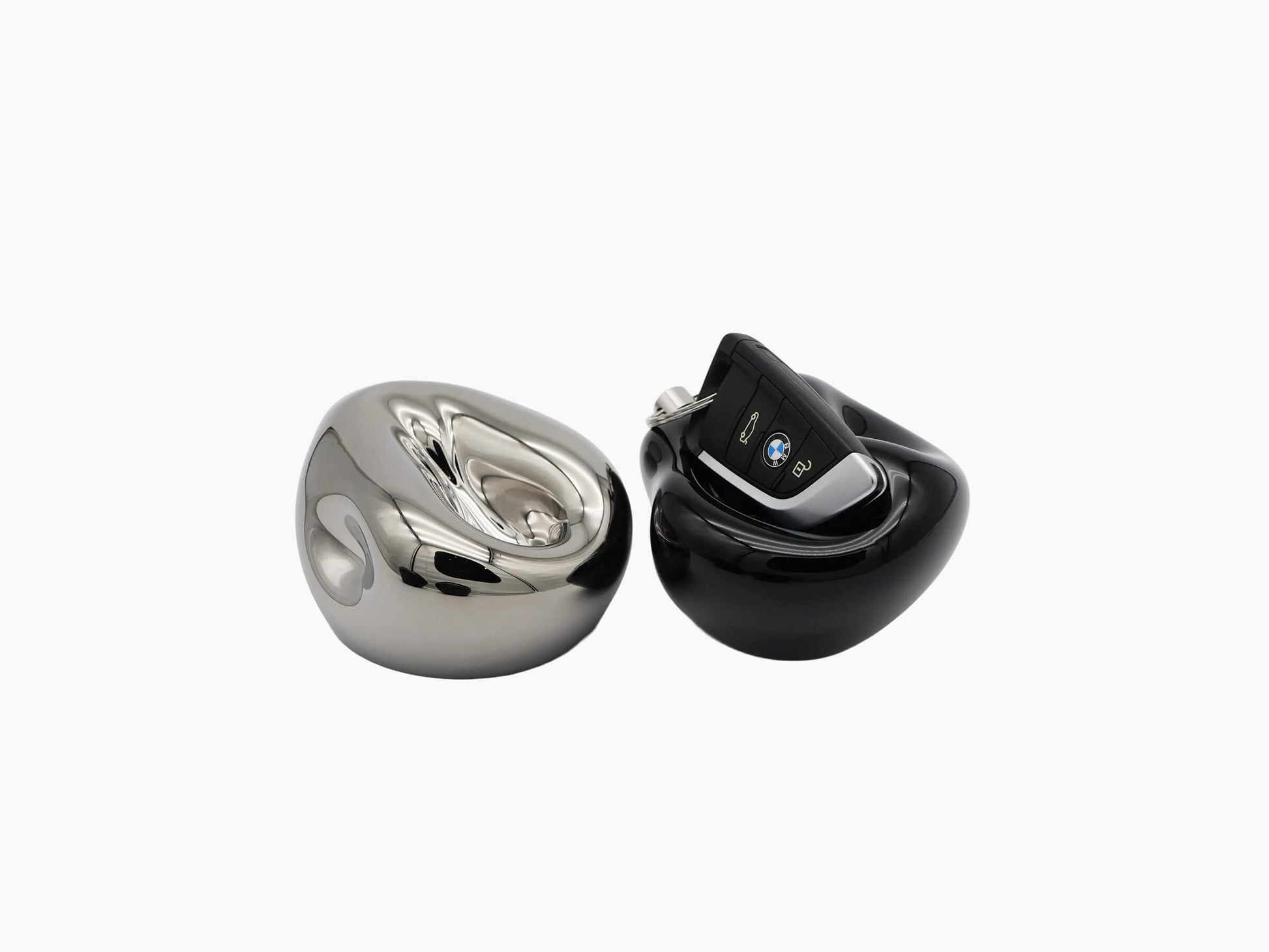 Pair of glossy vessels in Mercury Silver and black with a BMW car key resting on the black piece