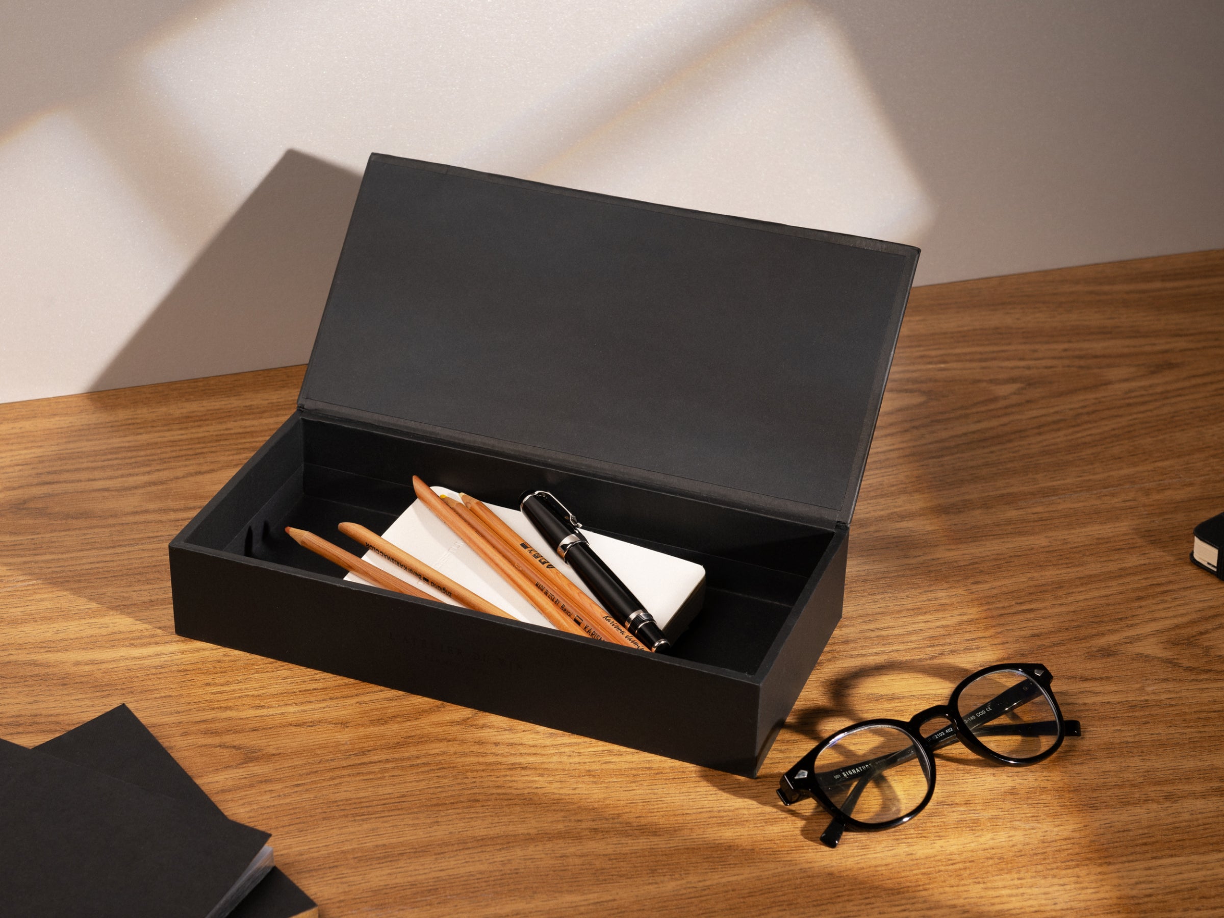 Oeno Collection 3 compact wine tools in a black open box on a wooden desk with glasses nearby