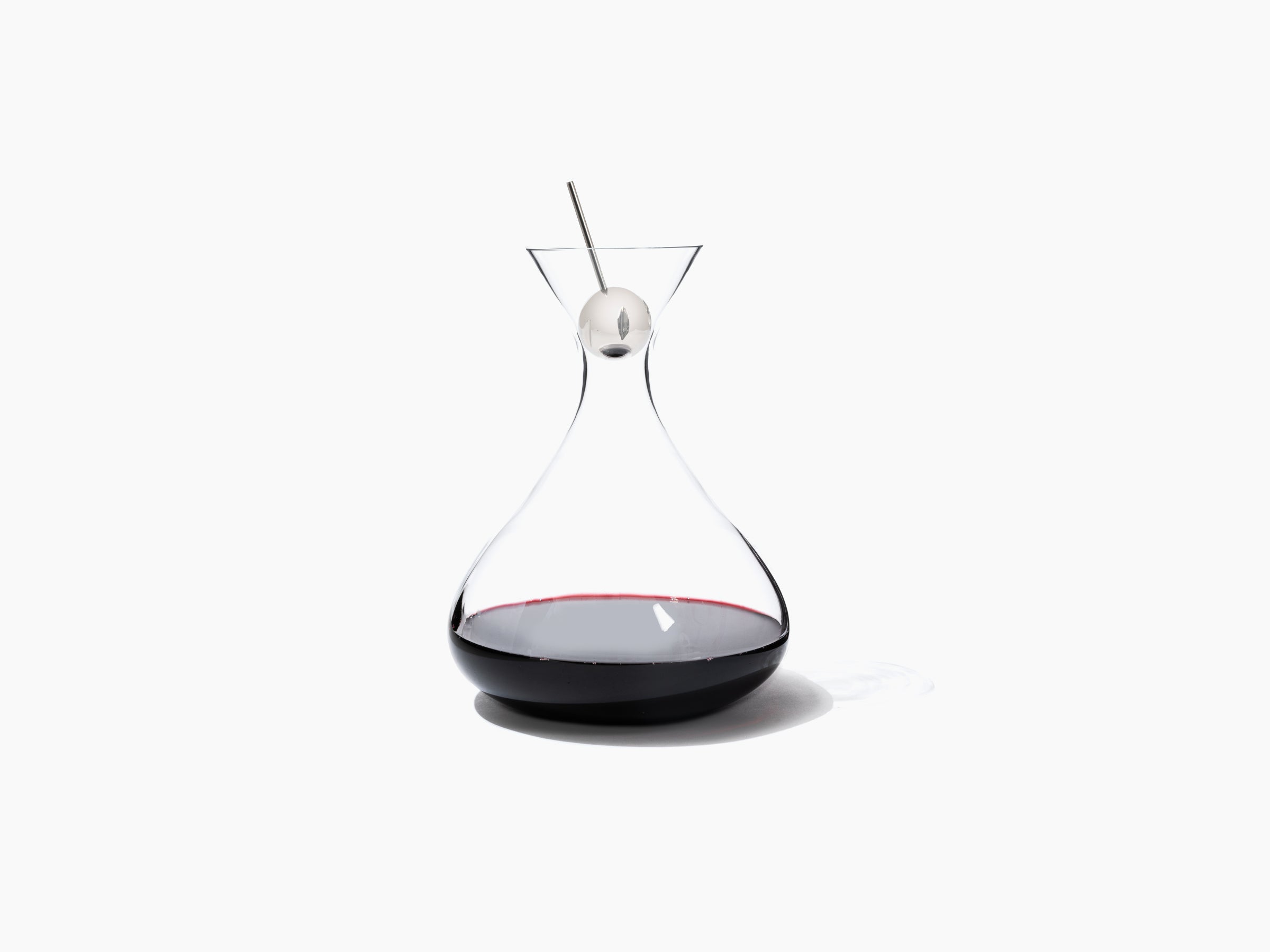Open Cristal Developer glass decanter with aroma ball and metal infusion rod over a glass of red wine