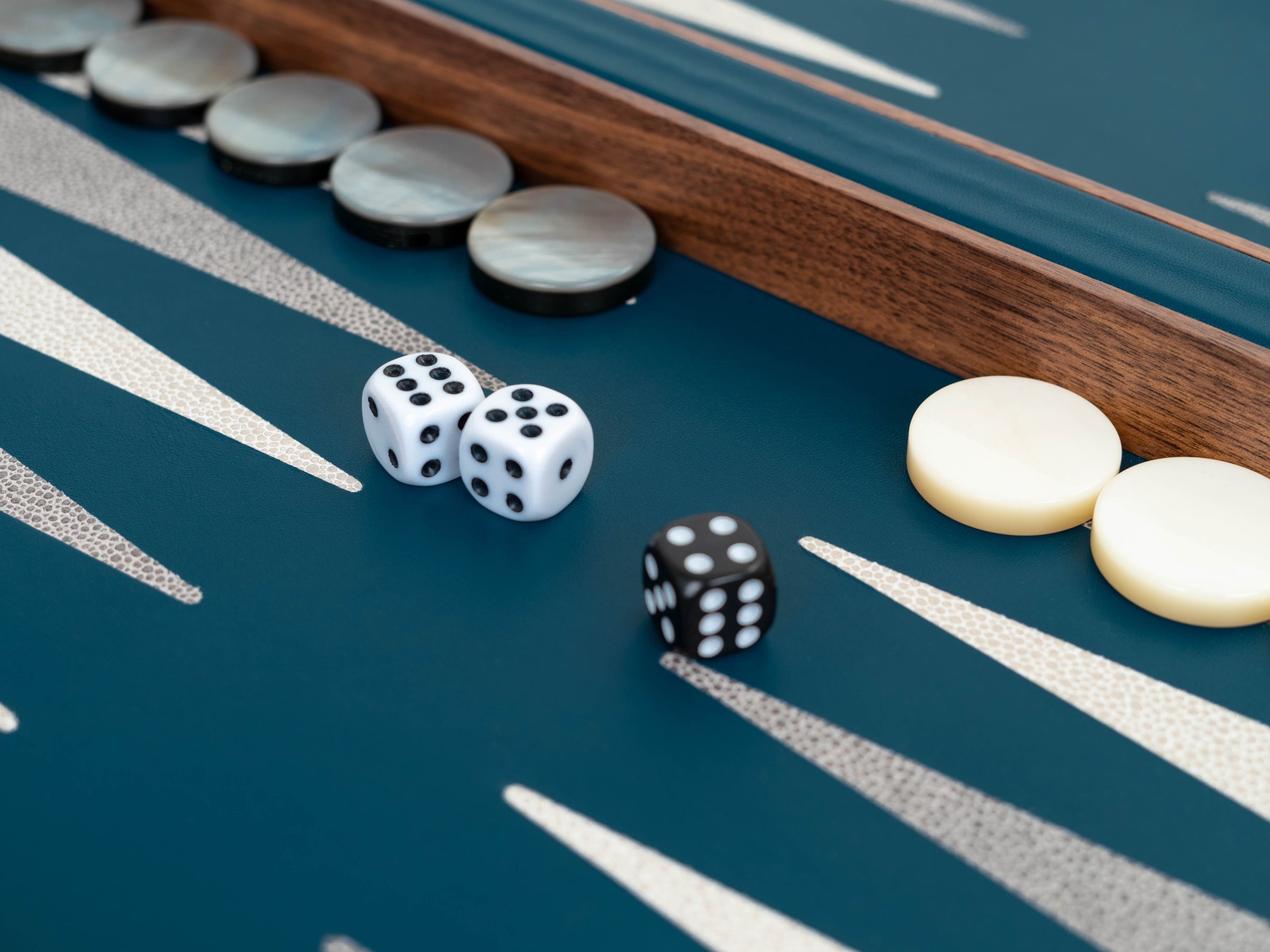 Backgammon set with dice and round checkers on a blue surface.